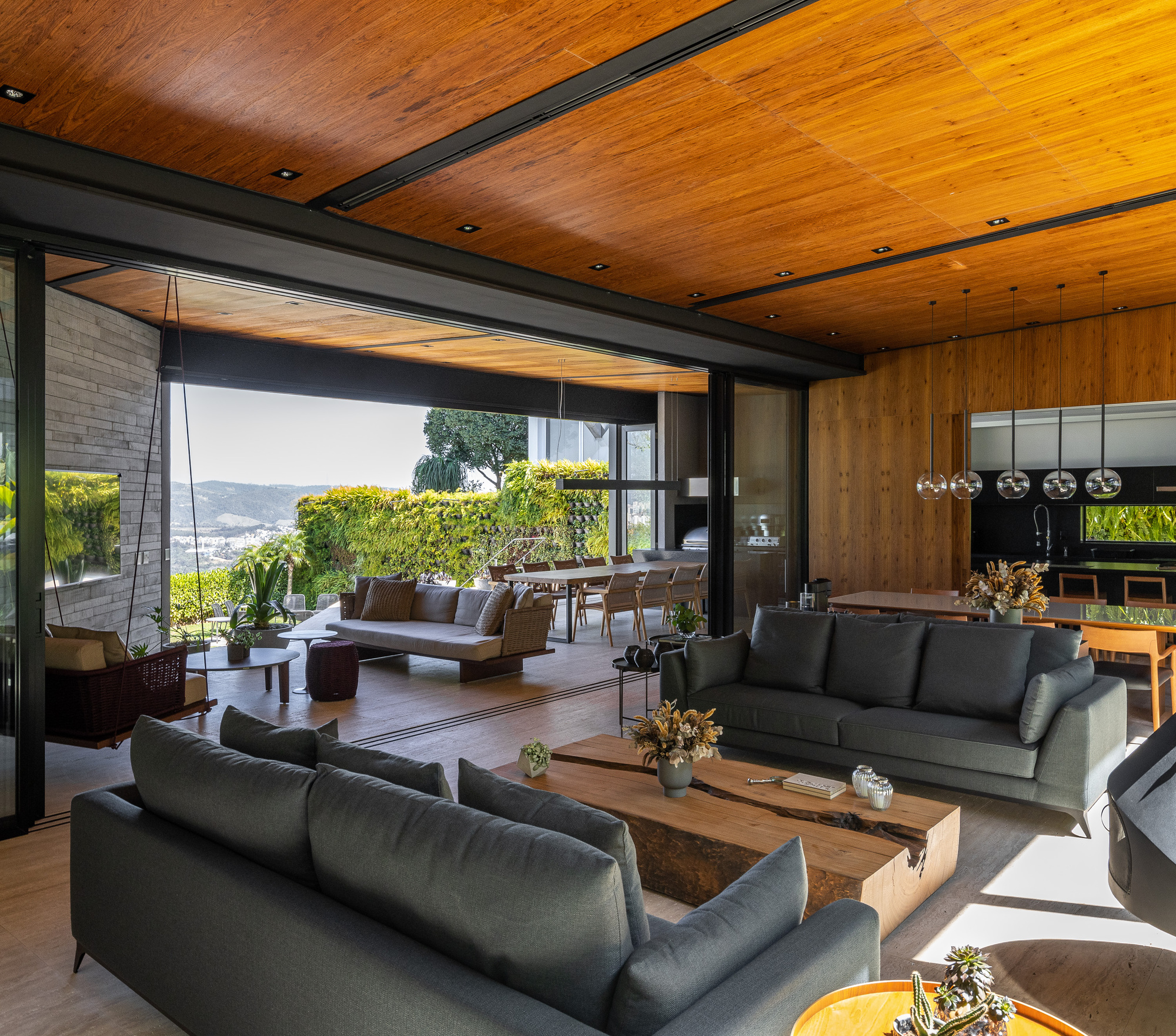 Open plan living space with exposed timber ceiling beams and full-height glazing opening to a terrace