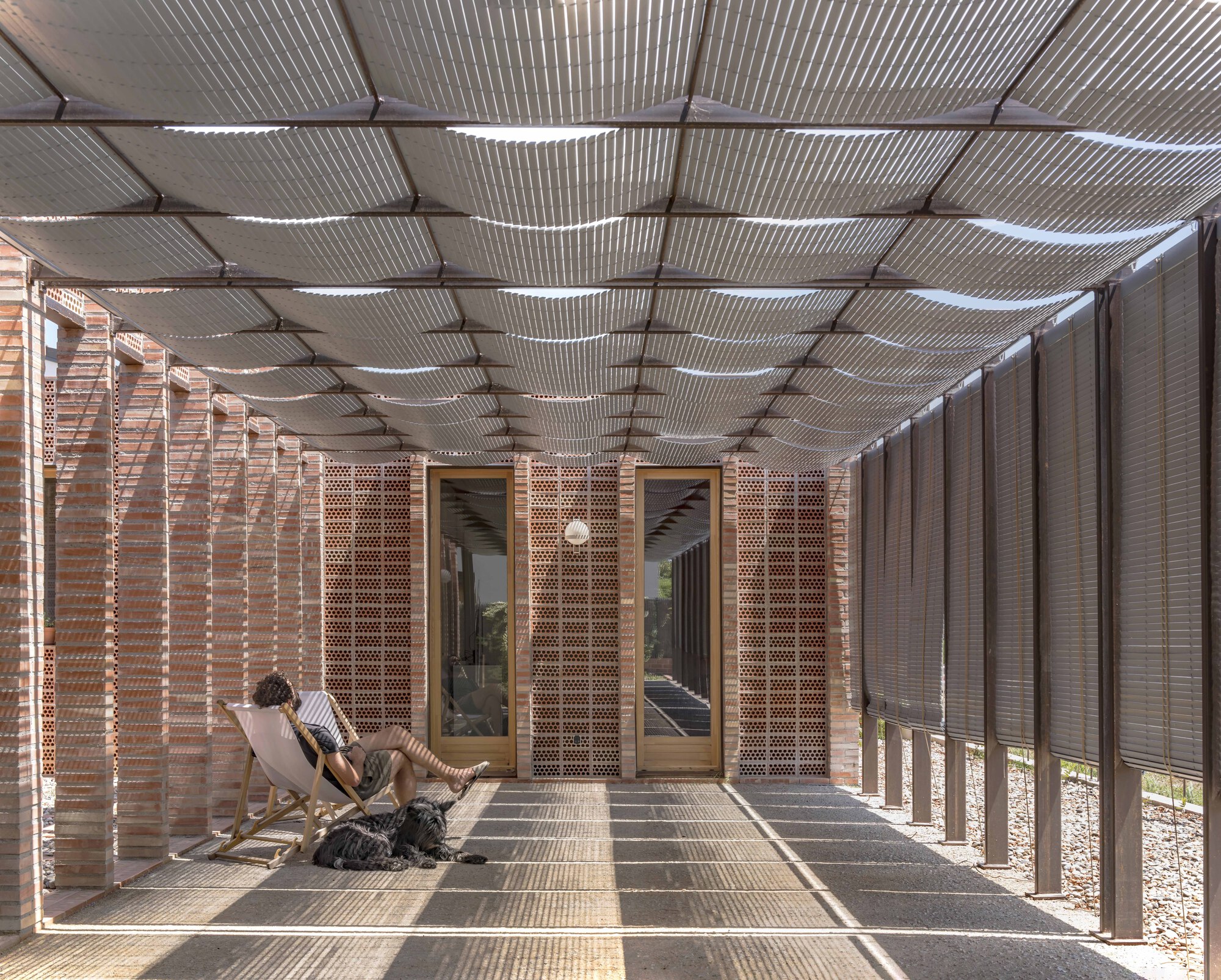 Covered porch with corrugated metal ceiling and perforated brick screens filtering afternoon light