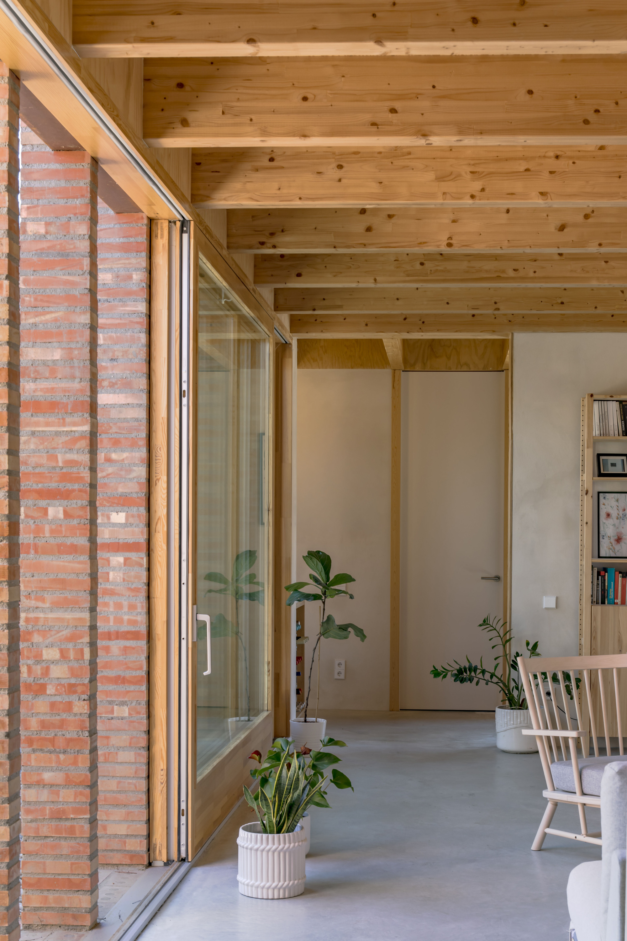 Interior hallway with exposed timber ceiling joists and sliding glass doors beside perforated brickwork