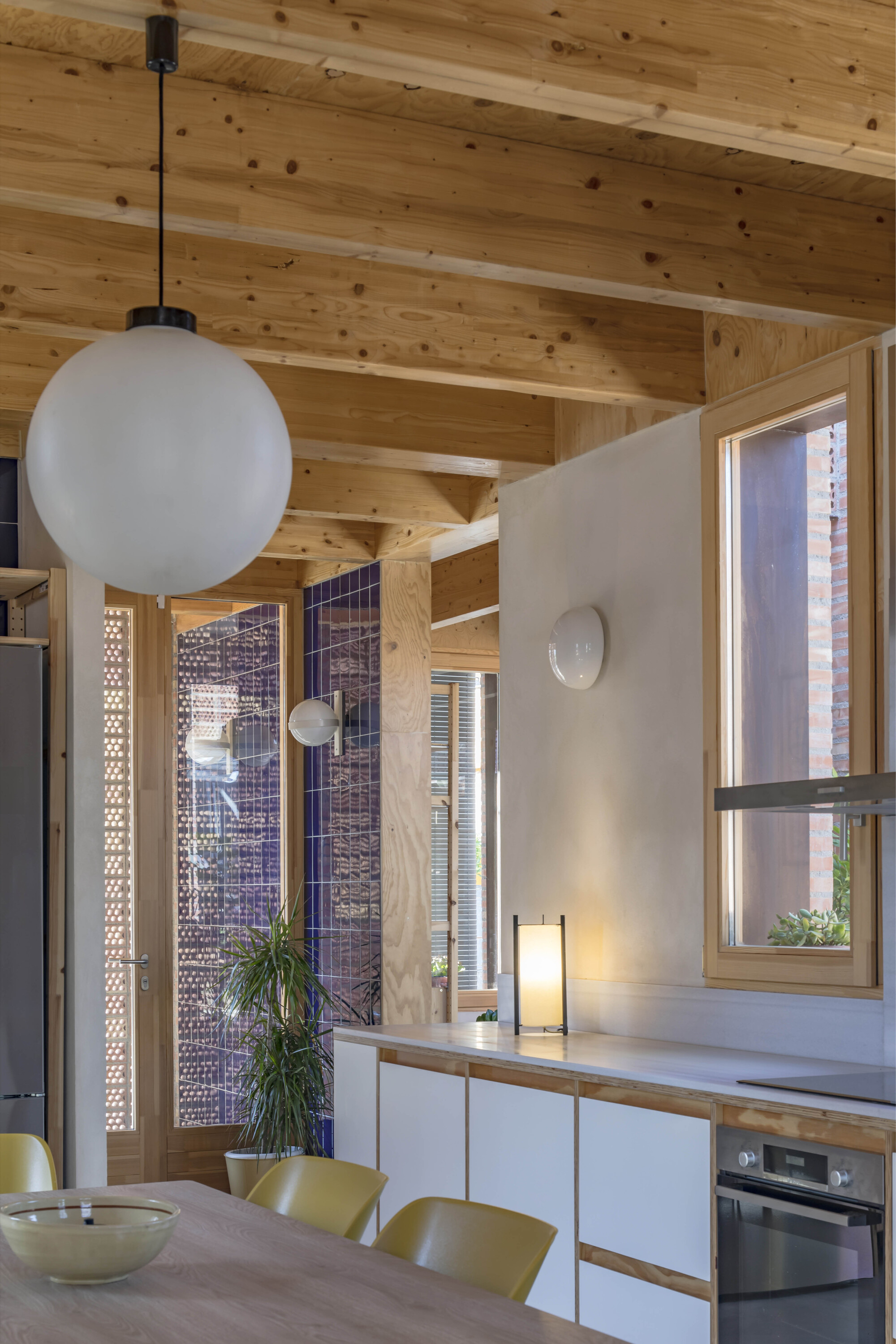 Dining area with spherical pendant light under exposed timber beams and perforated brick screens beyond