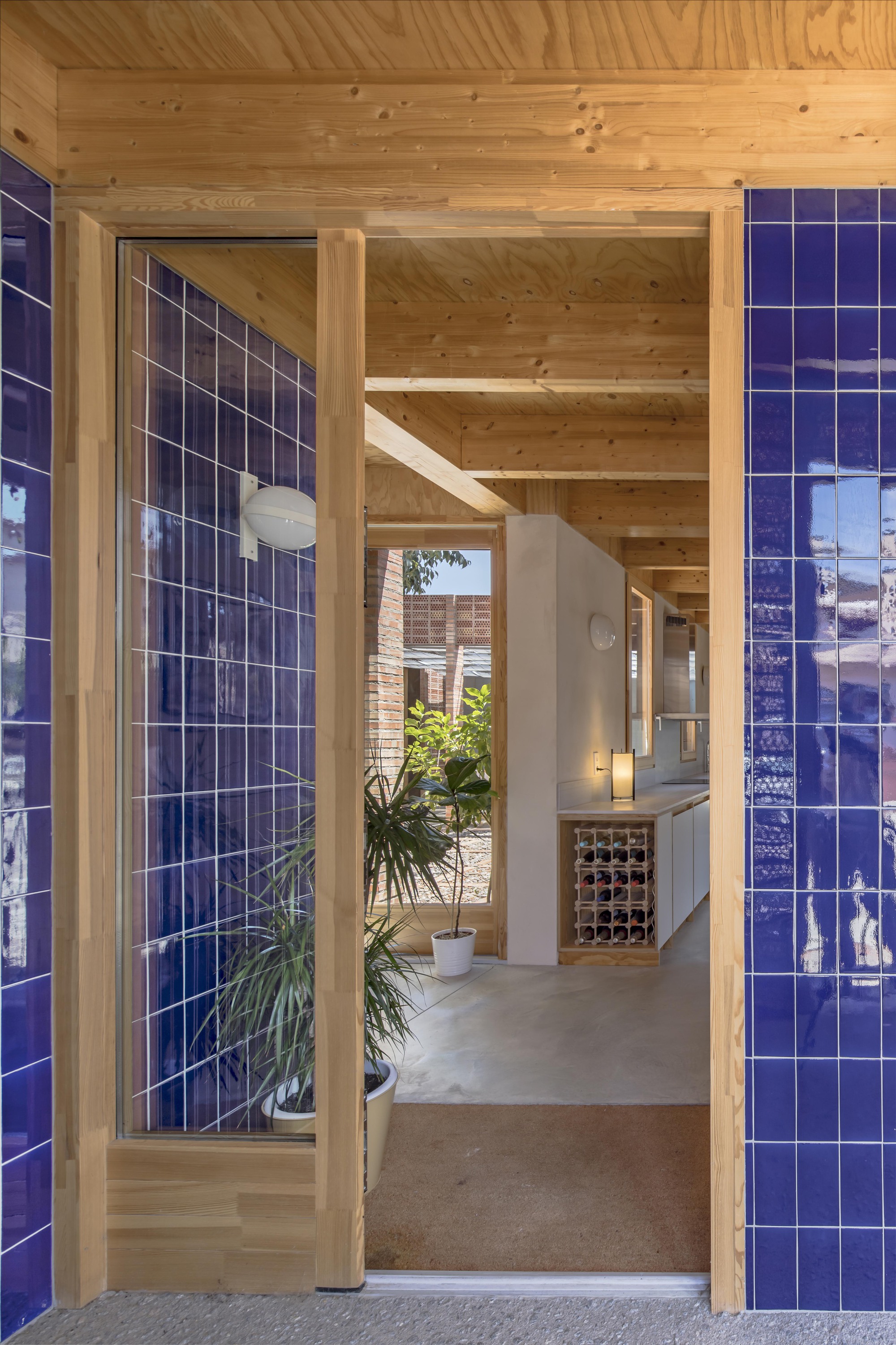 Timber-framed entrance with blue glazed tile walls and potted plants in the interior hallway