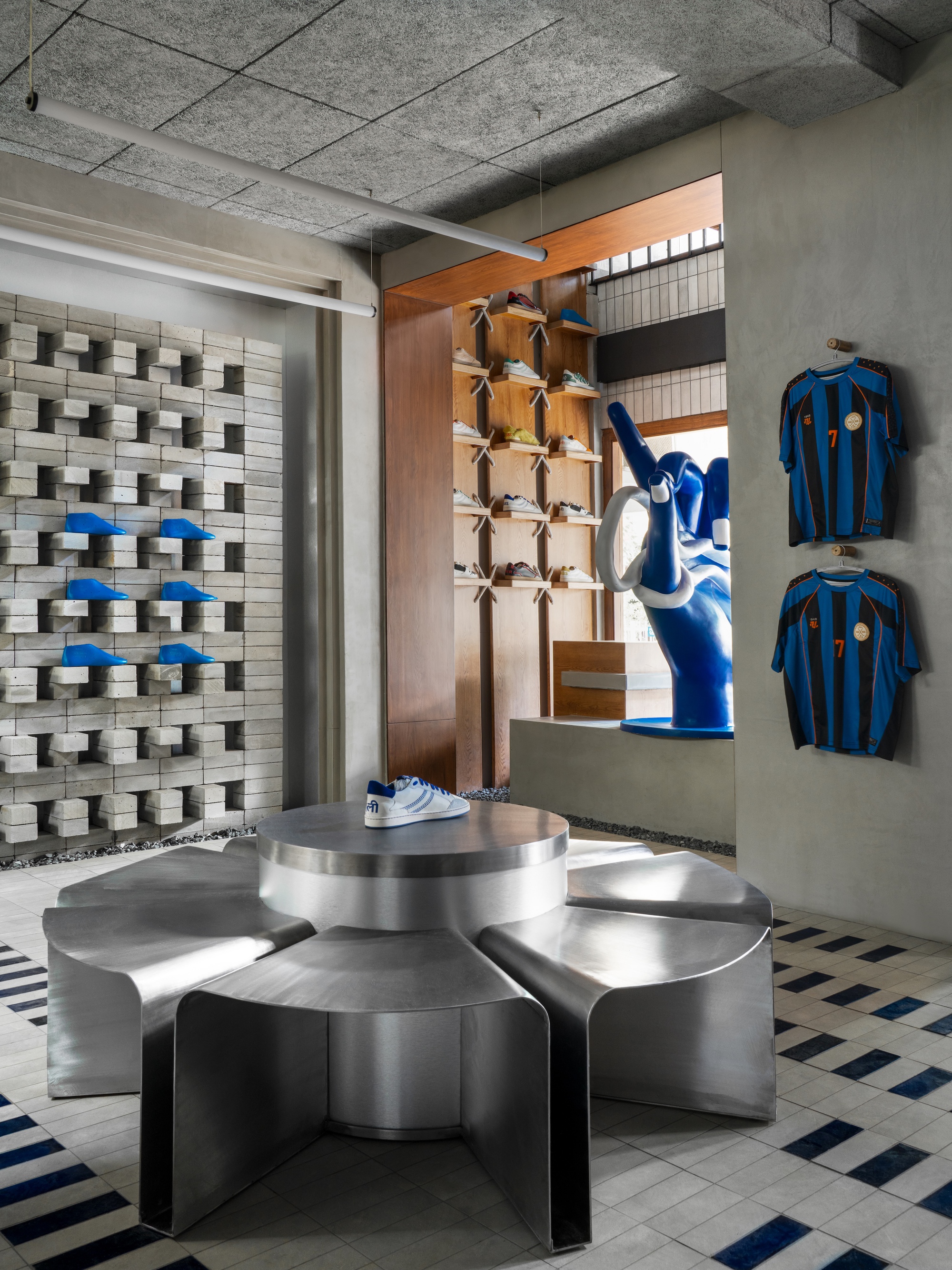 Stainless steel display table in front of timber-lined niche with merchandise and textured masonry wall