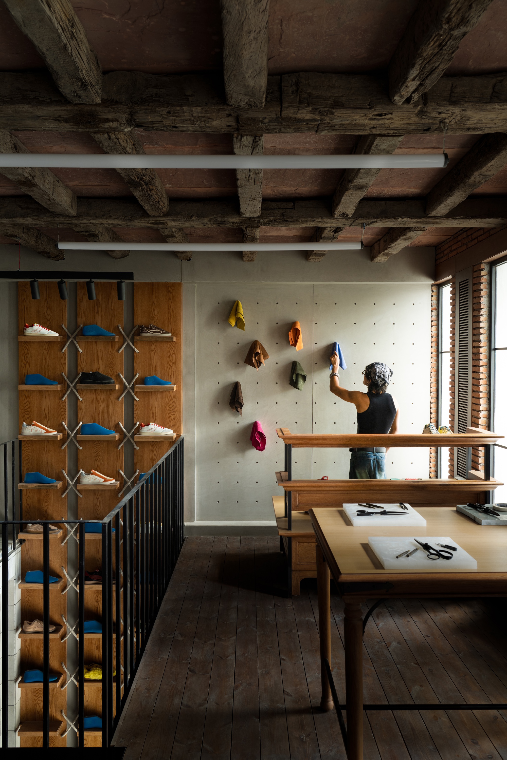 Interior workspace showing pegboard wall with colorful cap display and exposed timber ceiling structure above