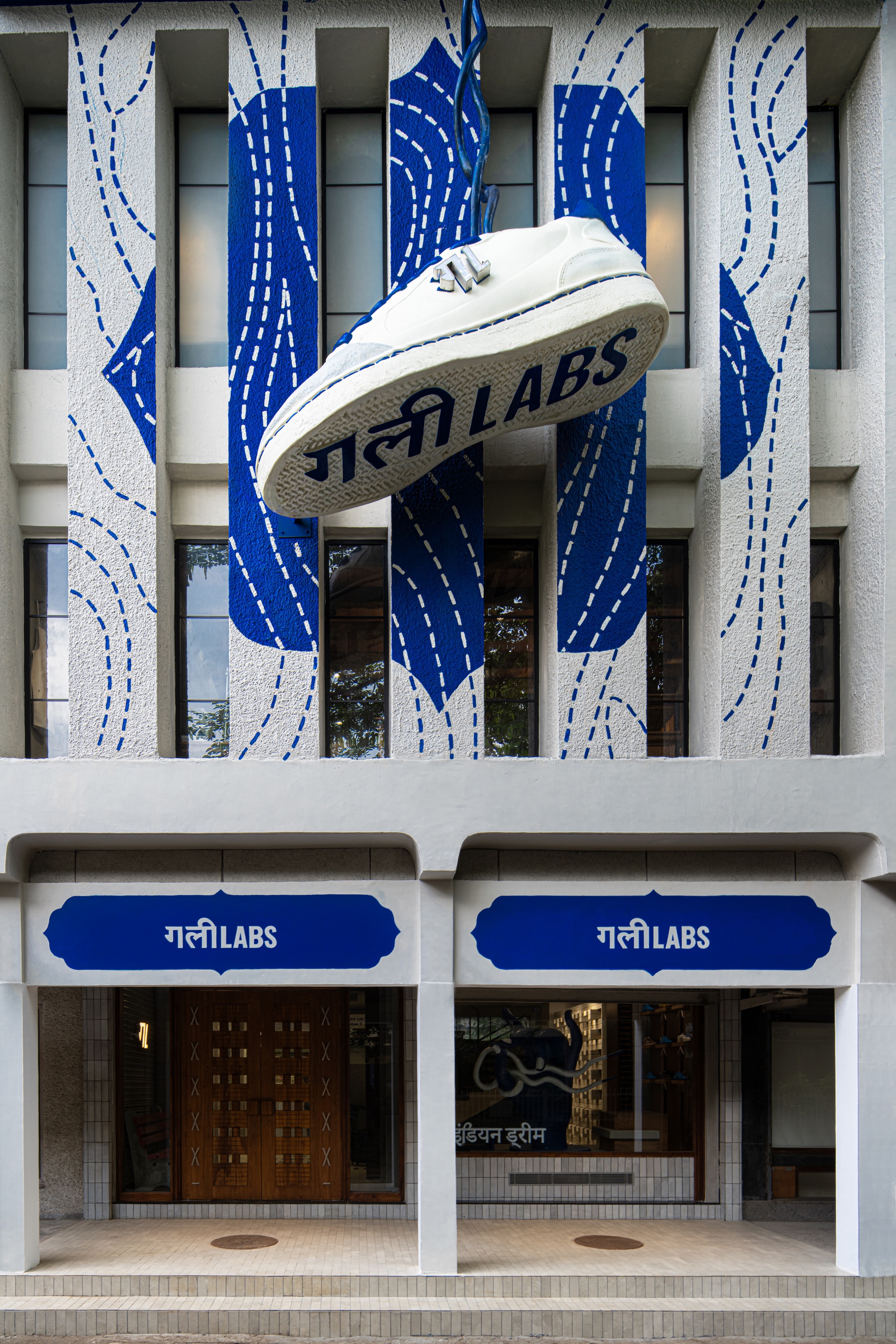 Close-up of the suspended white sneaker above the ground-level entrance with dual blue awnings