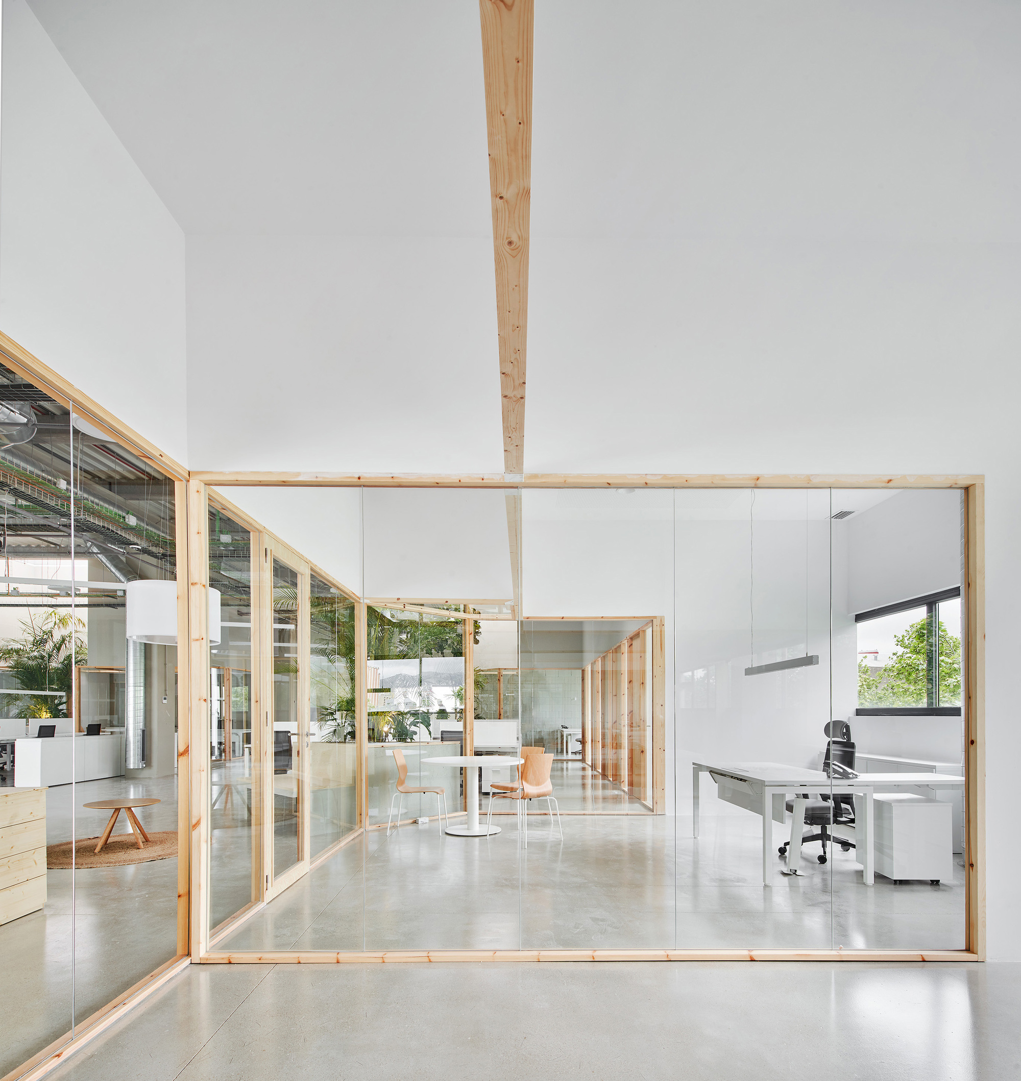 Glass-walled office enclosure with timber frame and central wood column on polished concrete floor