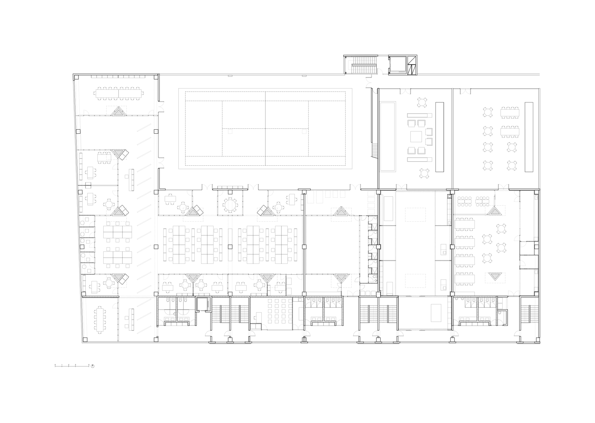 Floor plan drawing showing open work areas around central courtyard with surrounding enclosed rooms and staircases
