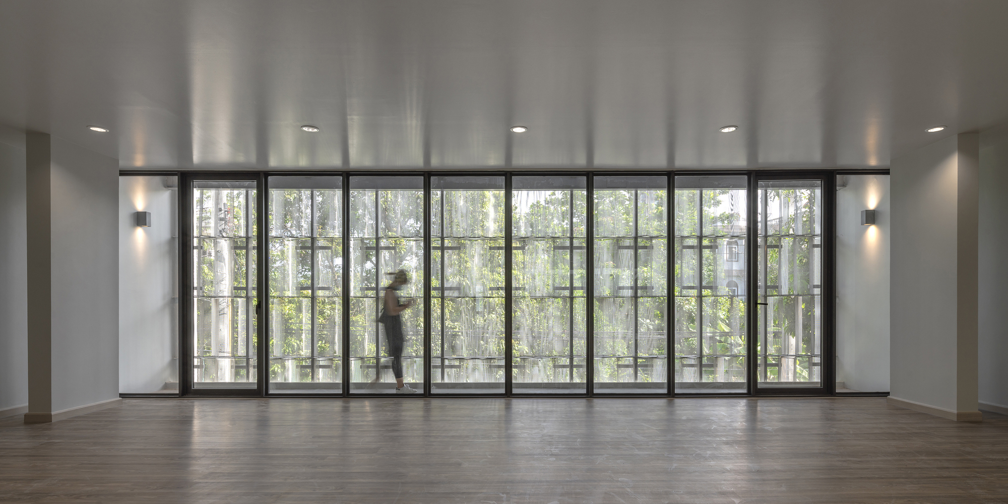 Interior room with floor-to-ceiling glazed doors opening to a balcony with trees beyond