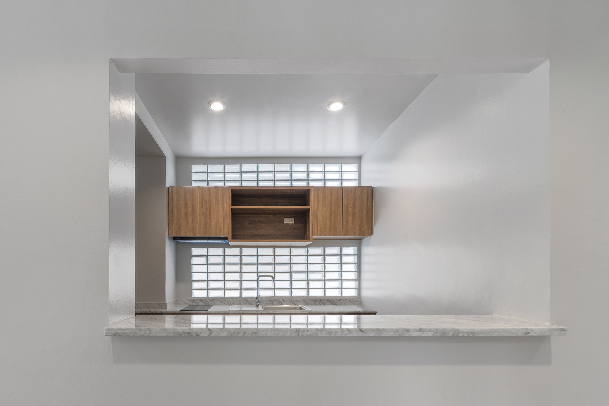 Kitchen pass-through with timber cabinetry and glass block windows above and below the counter