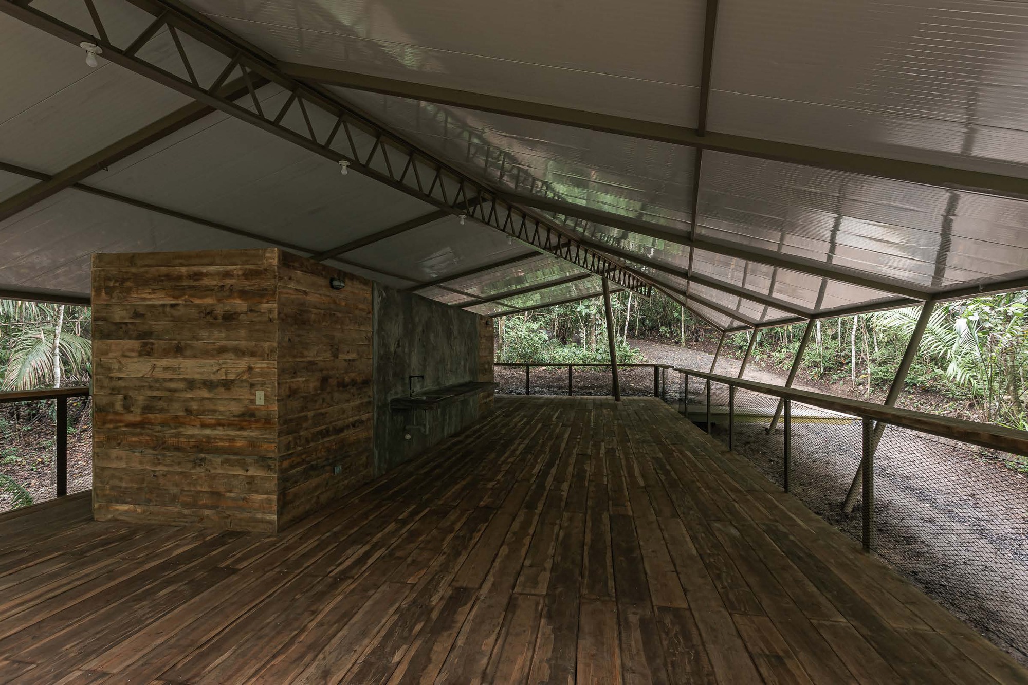 Interior deck with reclaimed wood flooring, timber service core, and exposed steel trusses under translucent panels