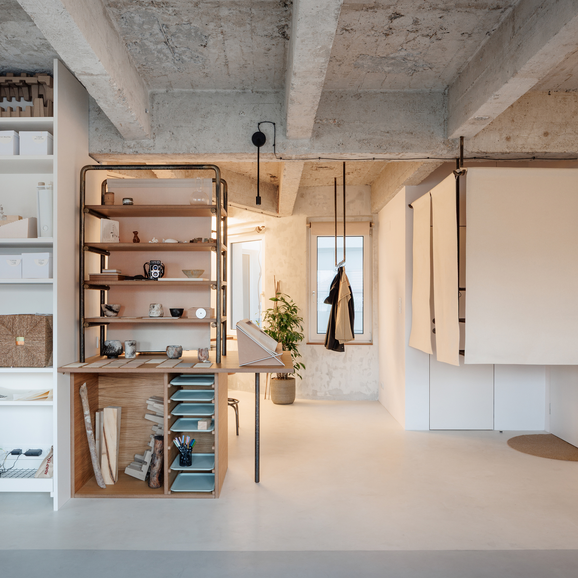 Freestanding shelving unit with timber frame and metal supports under an exposed concrete ceiling