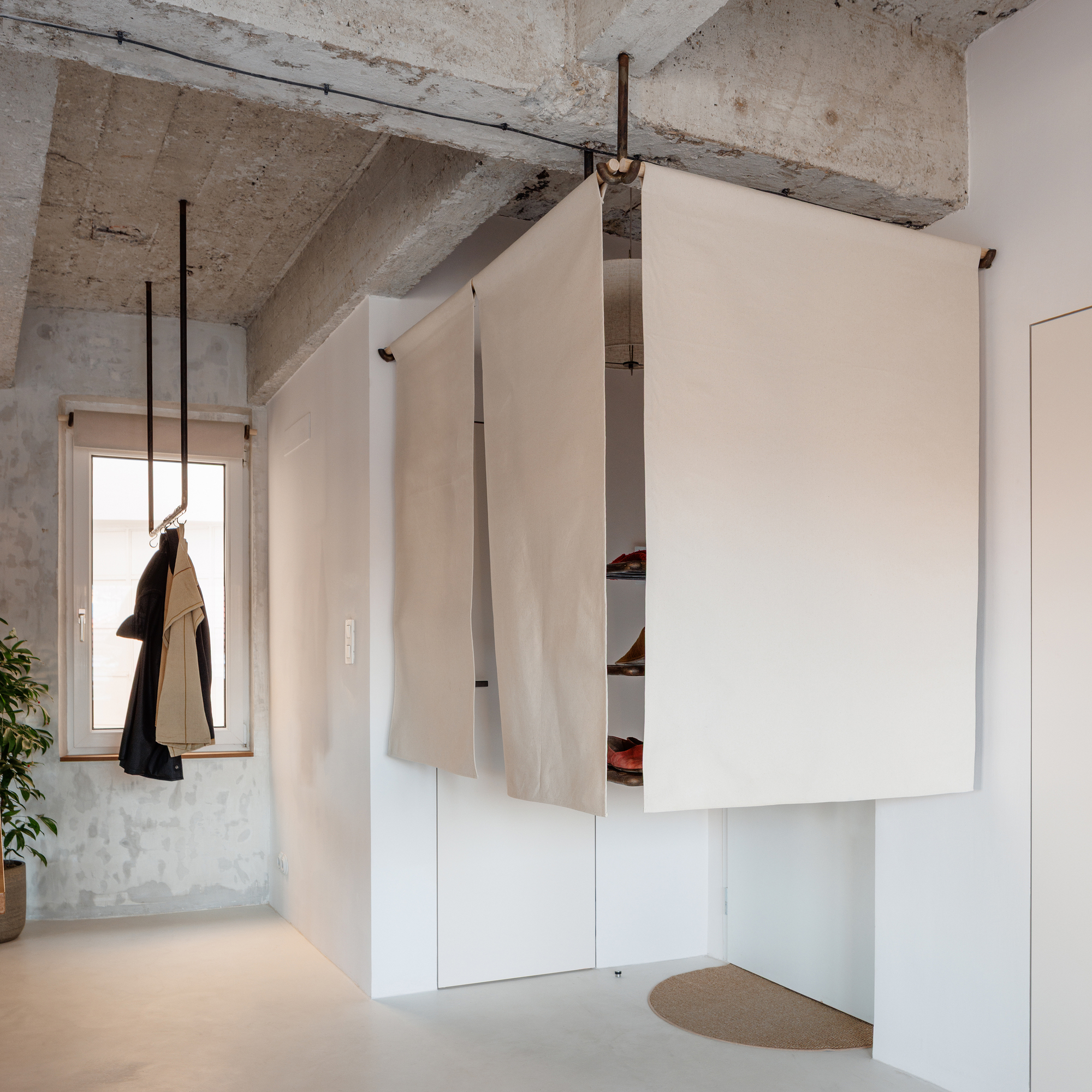 Corner storage unit with pivoting white panel revealing shelves beneath exposed concrete beams