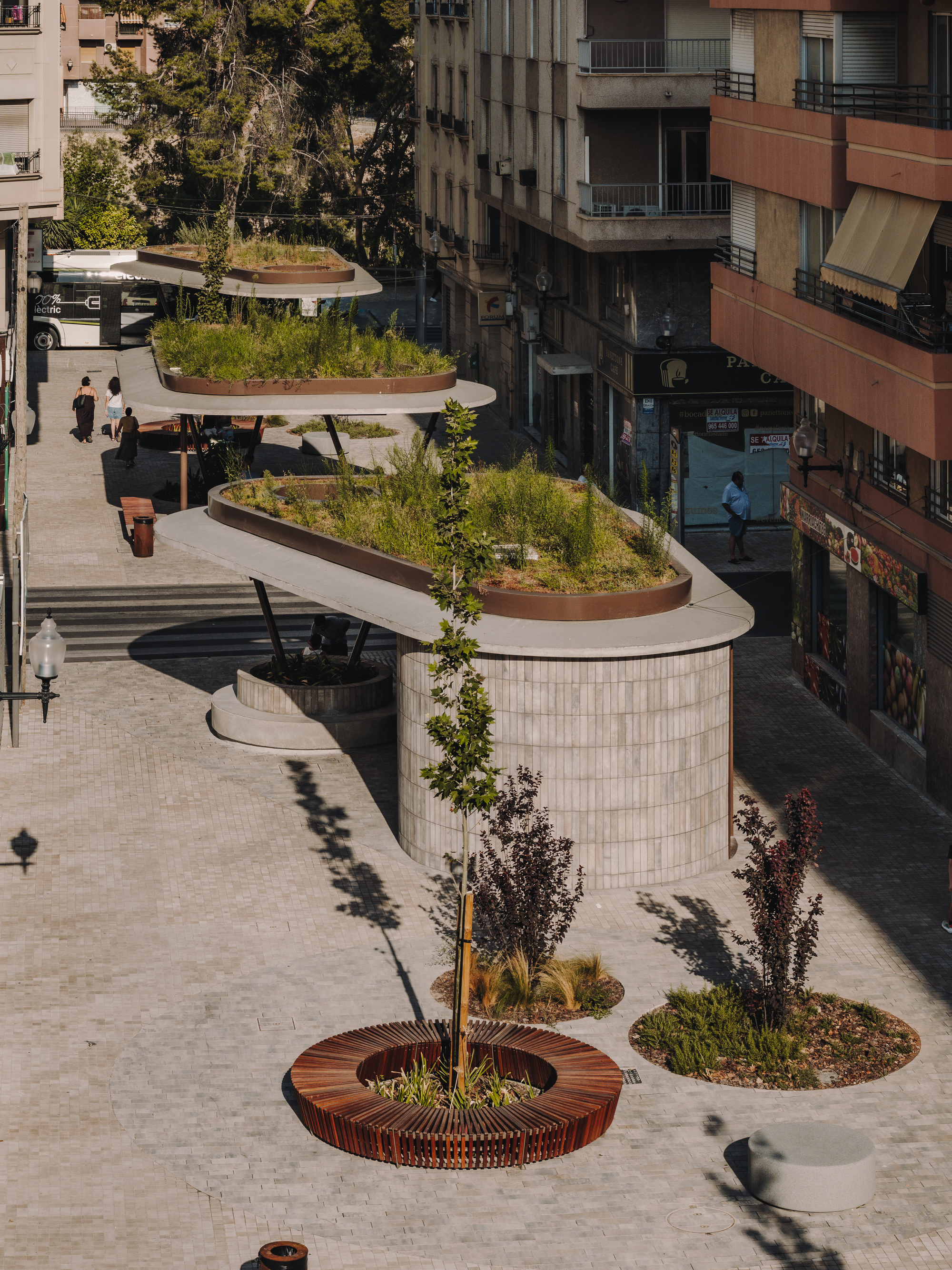 Aerial view of three tiered canopies with green roofs and circular timber tree grates in sunlight