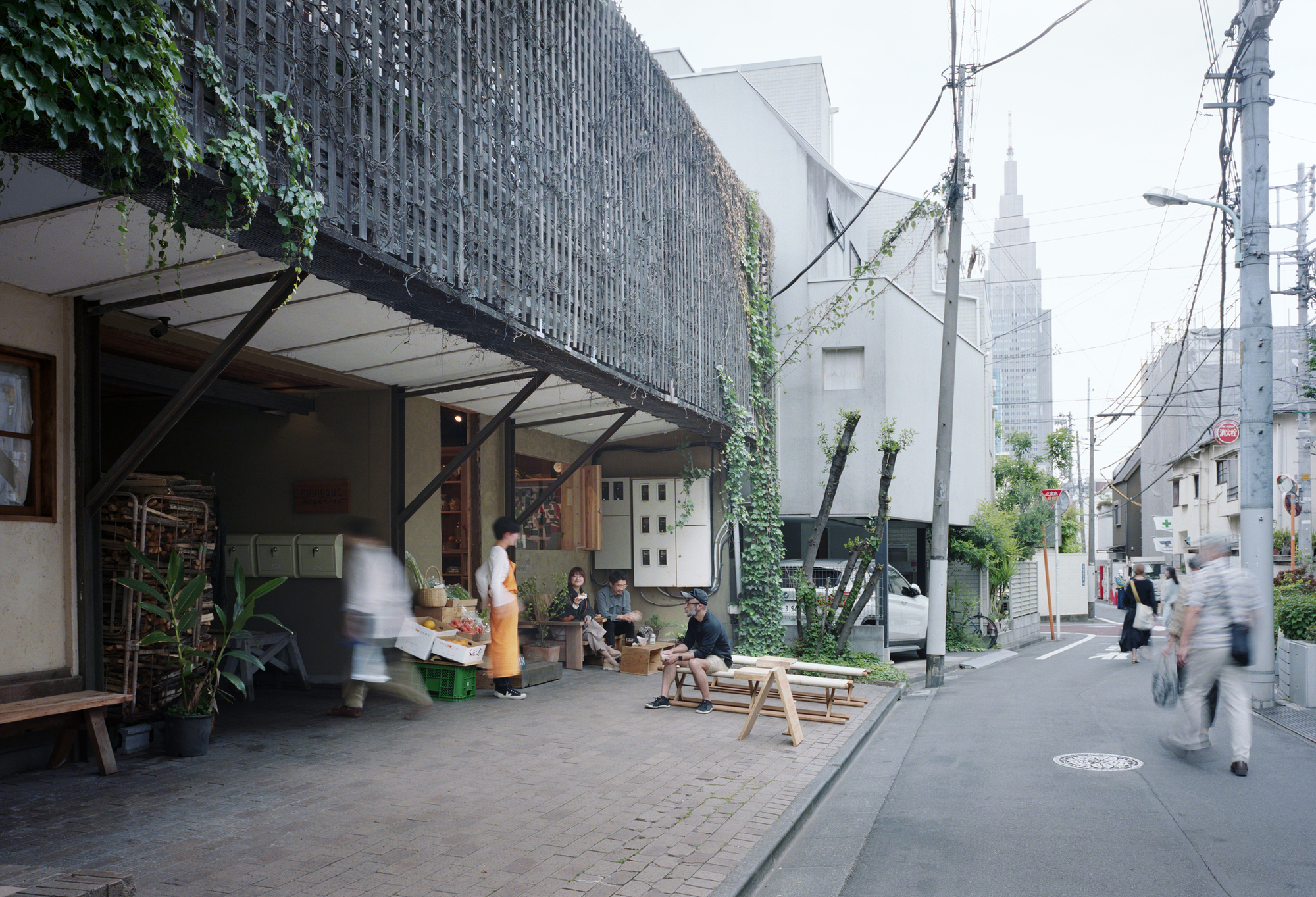 Perforated brick screen facade with steel bracing above a street-level shop terrace