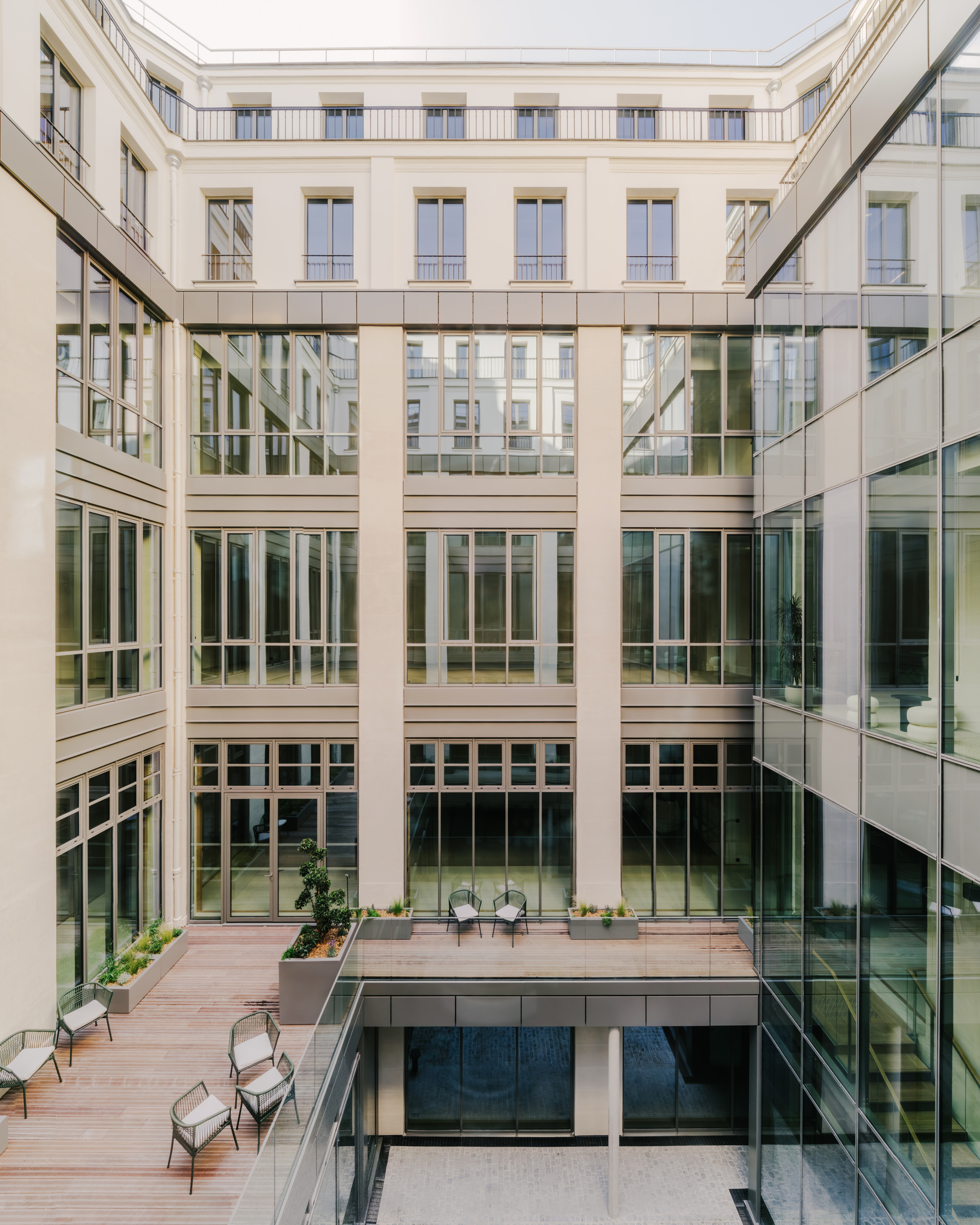 Interior courtyard with glass-enclosed volumes and diagonal structural bracing spanning between glazed facades
