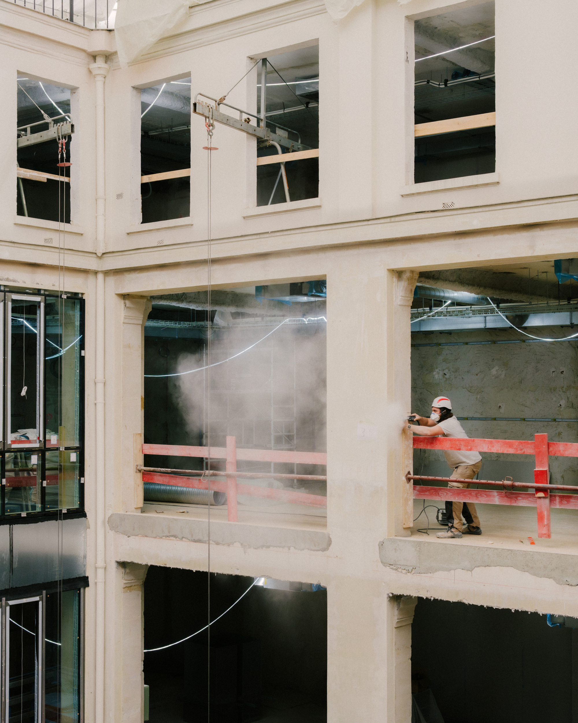 Multi-level courtyard section with a construction worker standing behind red safety barriers