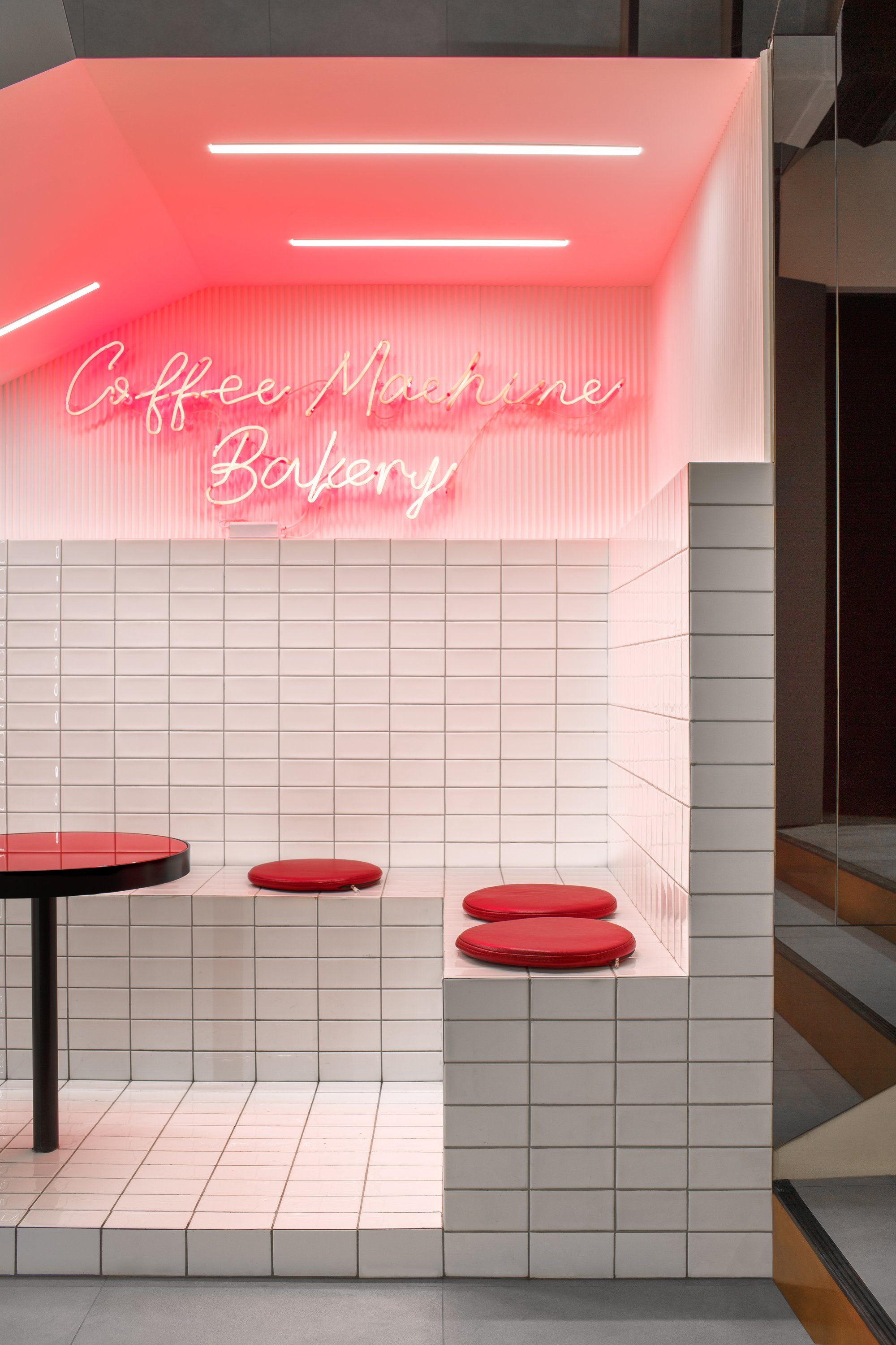 Sculpted tile seating under the staircase with neon identity