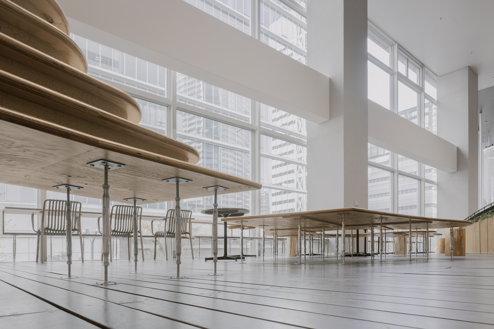 Light-filled upper level with cantilevered plywood shelves and tubular steel chairs facing gridded windows