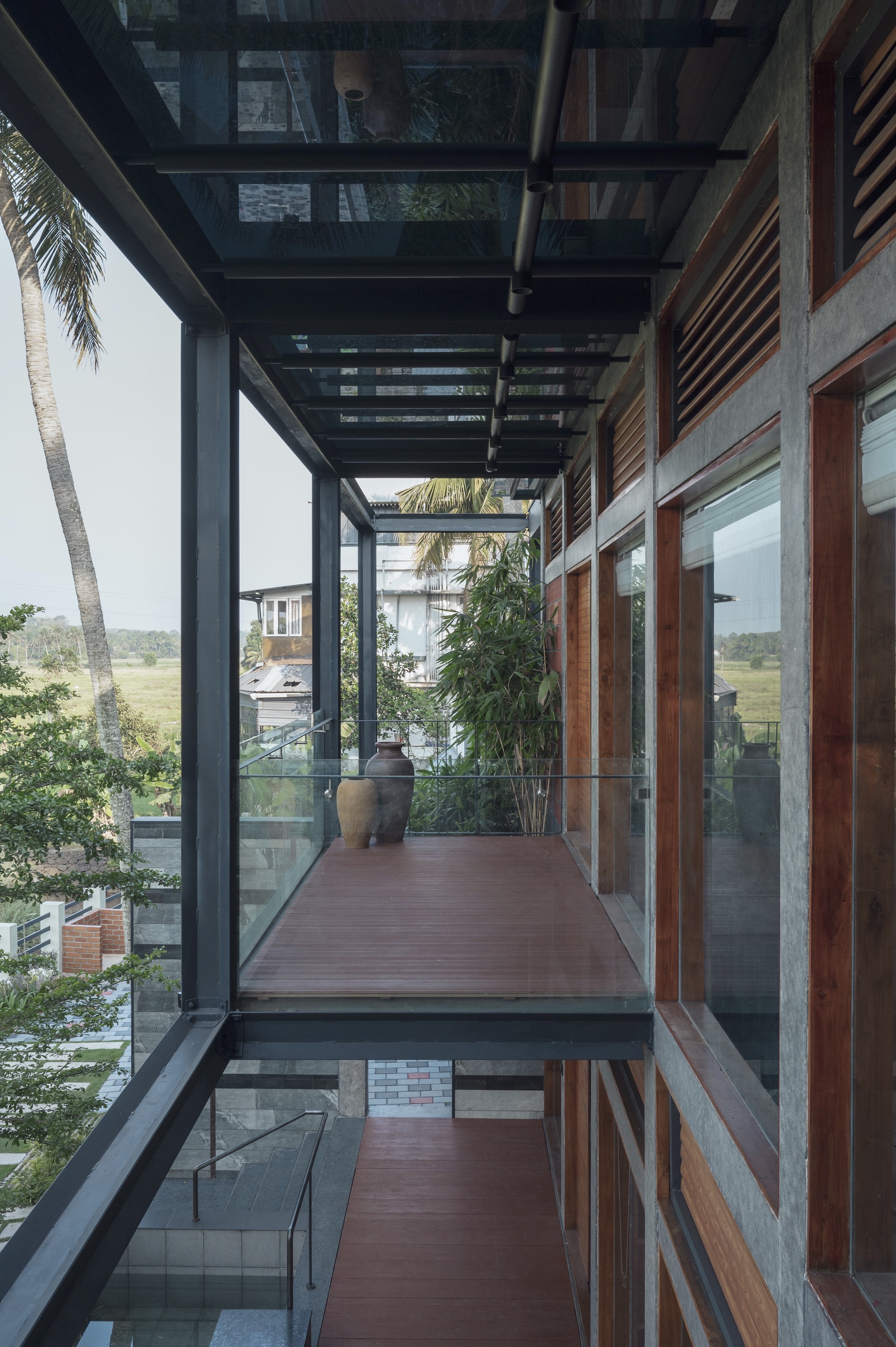 Covered walkway with steel pergola overhead and timber decking bridging between glazed volumes
