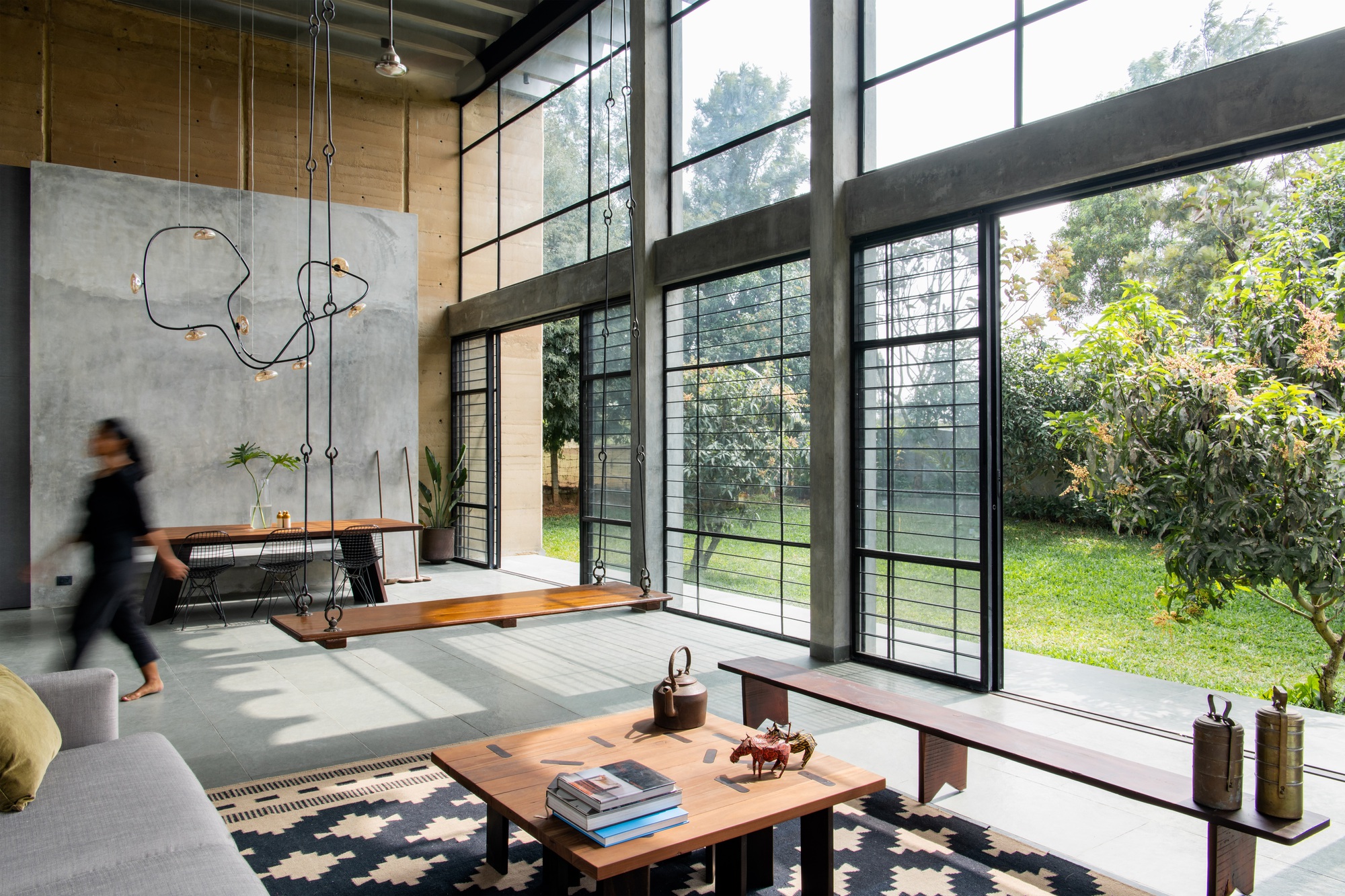 Living space with steel-framed doors opening to garden while a person walks past the concrete wall