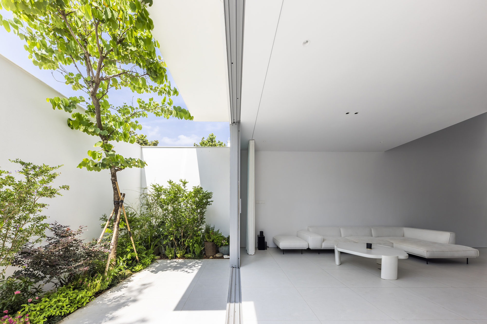 Interior terrace opening with retractable glass doors and planted courtyard garden under open sky