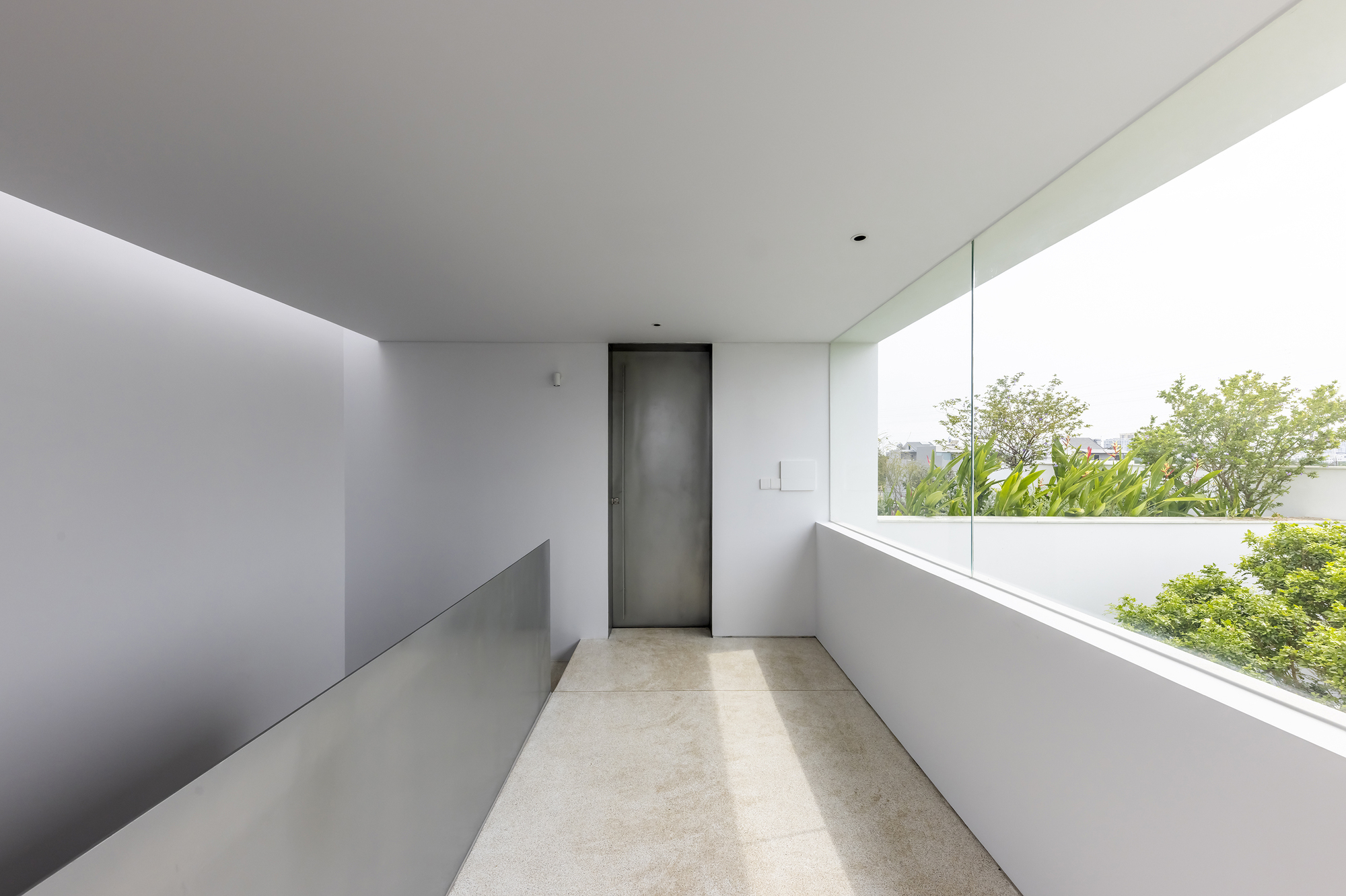 Upper-level corridor with terrazzo flooring and a horizontal window overlooking garden canopy