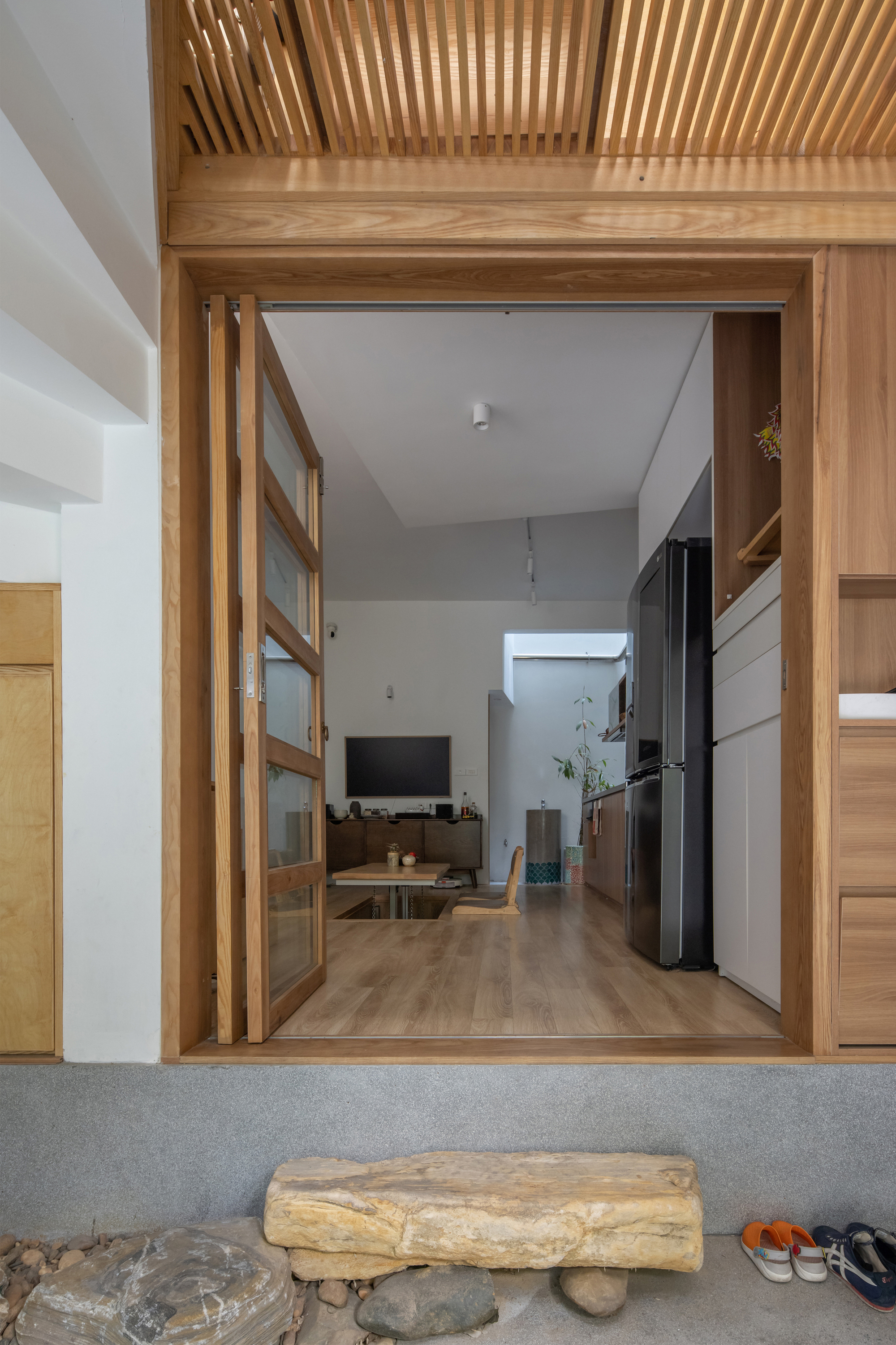 Threshold view through timber-framed sliding doors showing the slatted ceiling and living space beyond