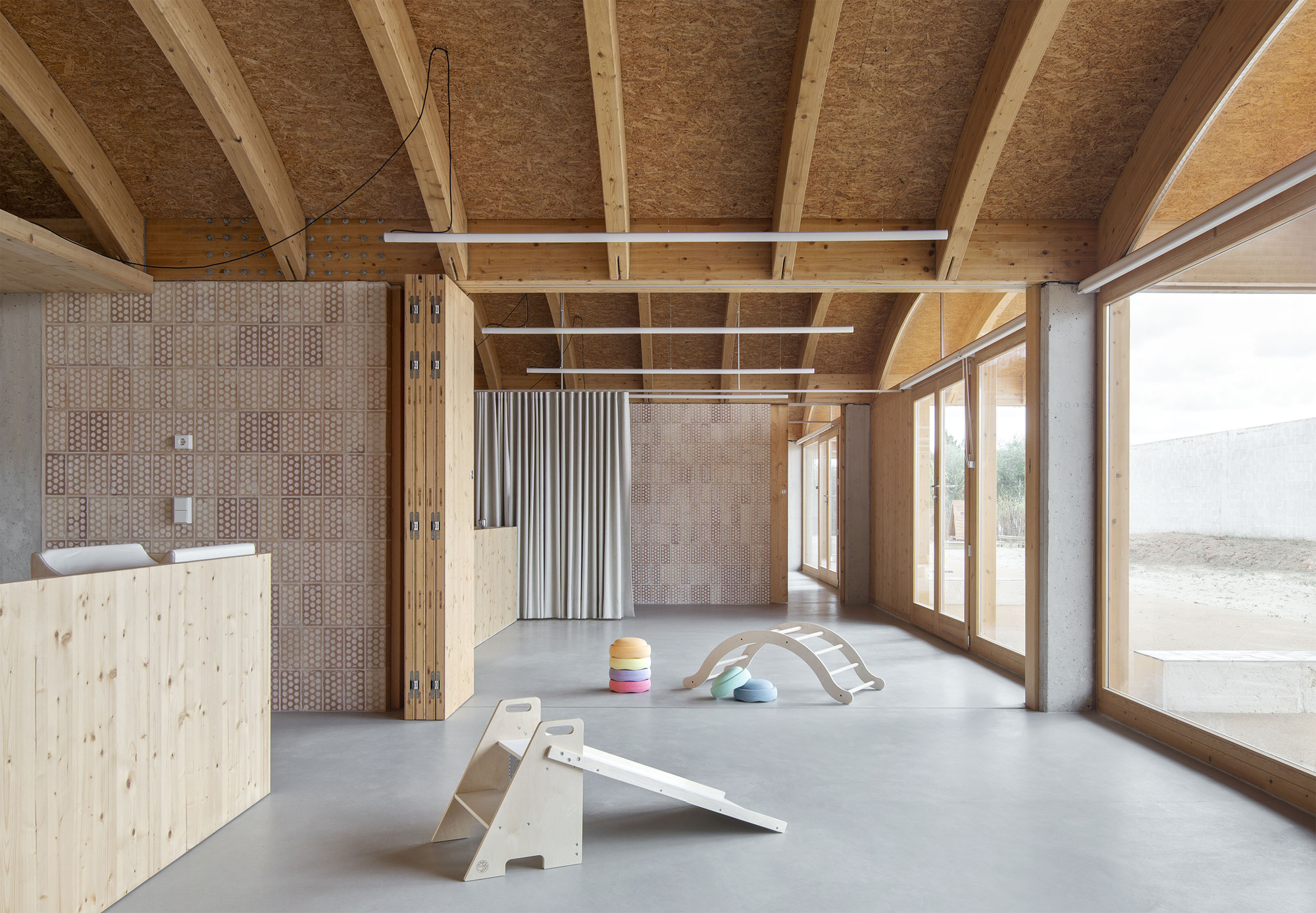 Interior with exposed timber ceiling beams and tiled wall panels dividing the polished concrete floor