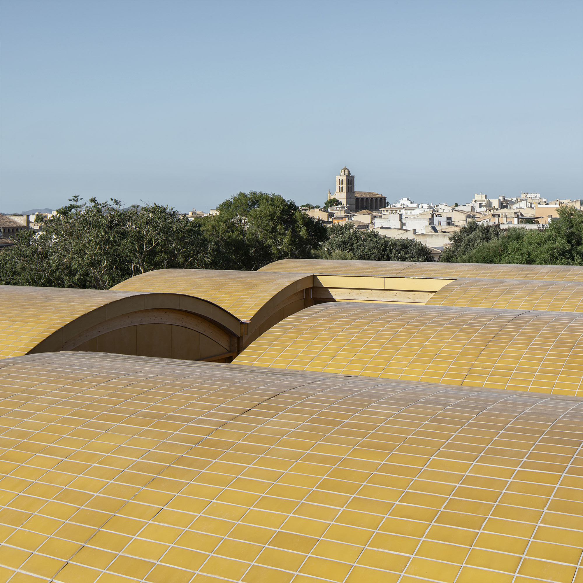 Rooftop view of the wave-form ceramic tile roof with a distant bell tower and village beyond