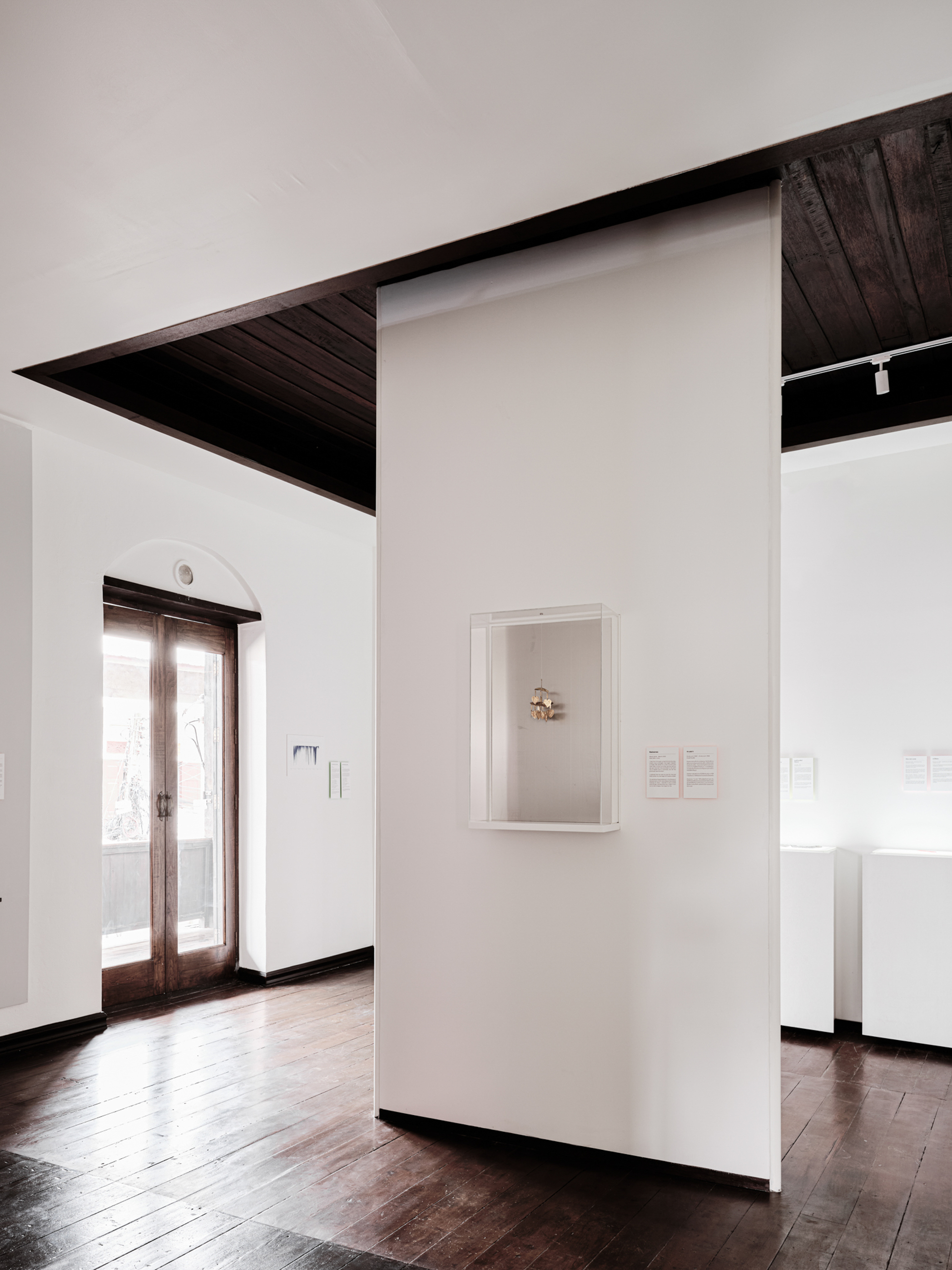 Framed artwork on a white partition wall with angular dark timber ceiling plane above
