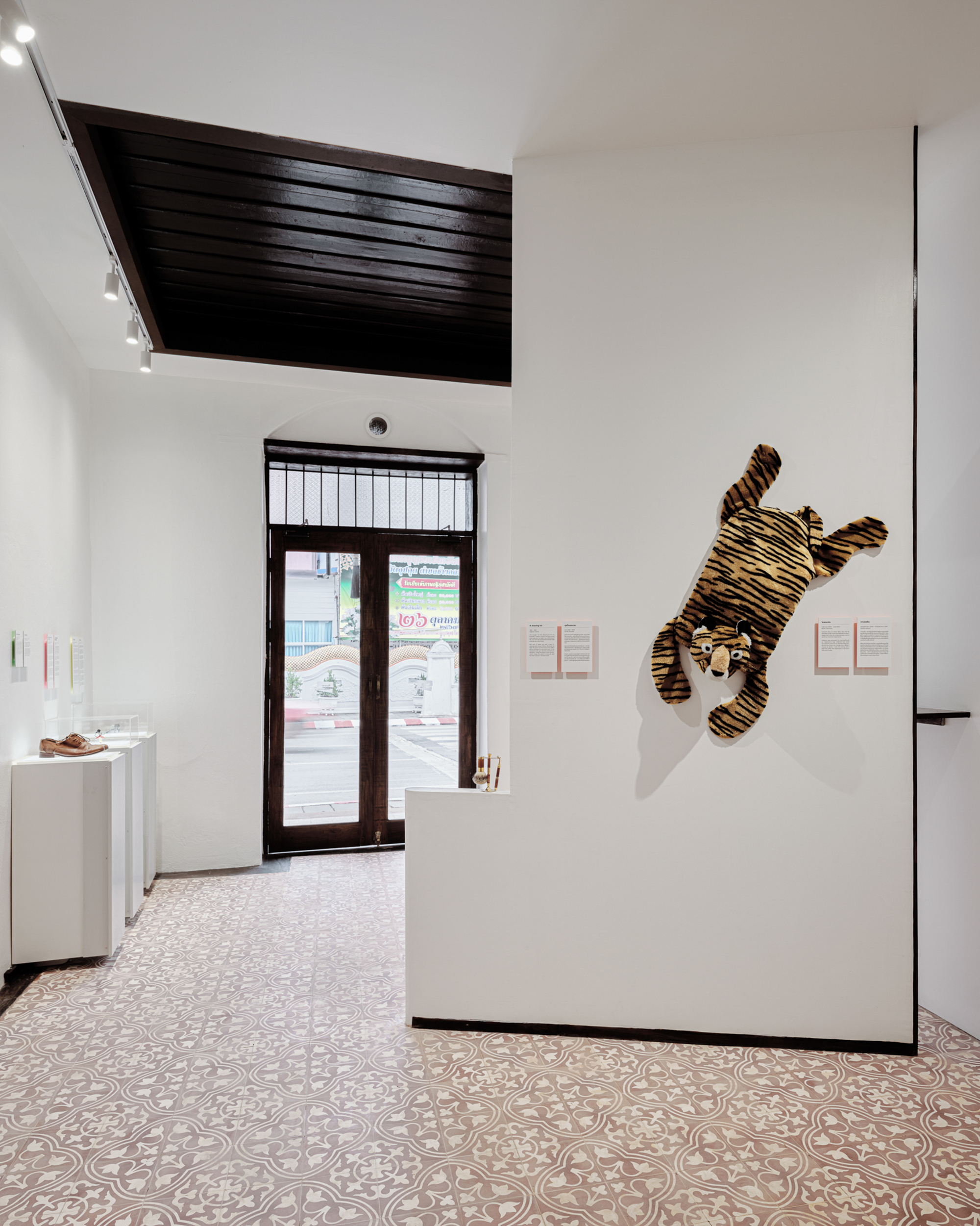 Entrance gallery with patterned tile floor and striped sculpture mounted on a white partition wall