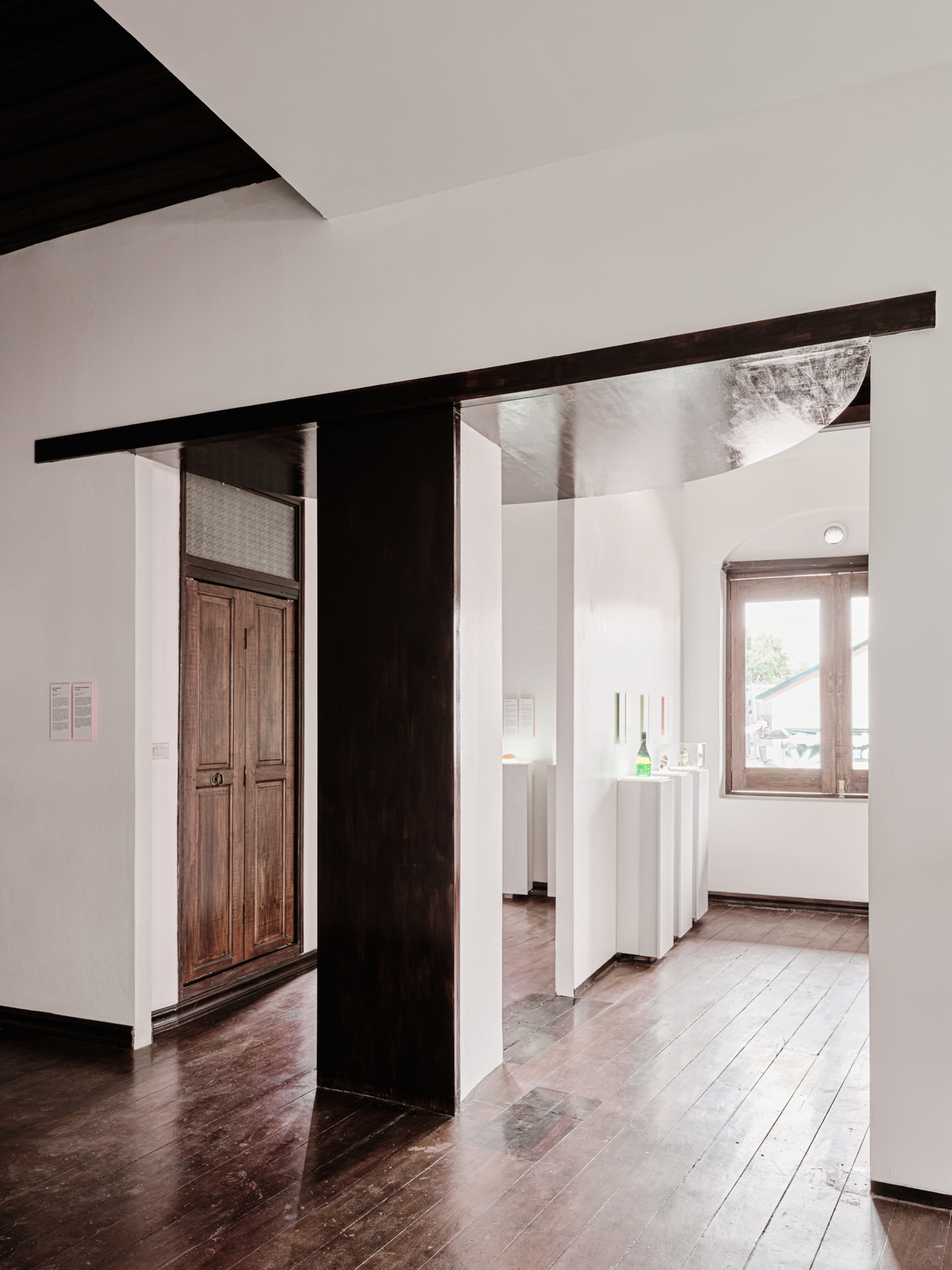 View through blackened steel frame into adjacent gallery rooms with timber door and window