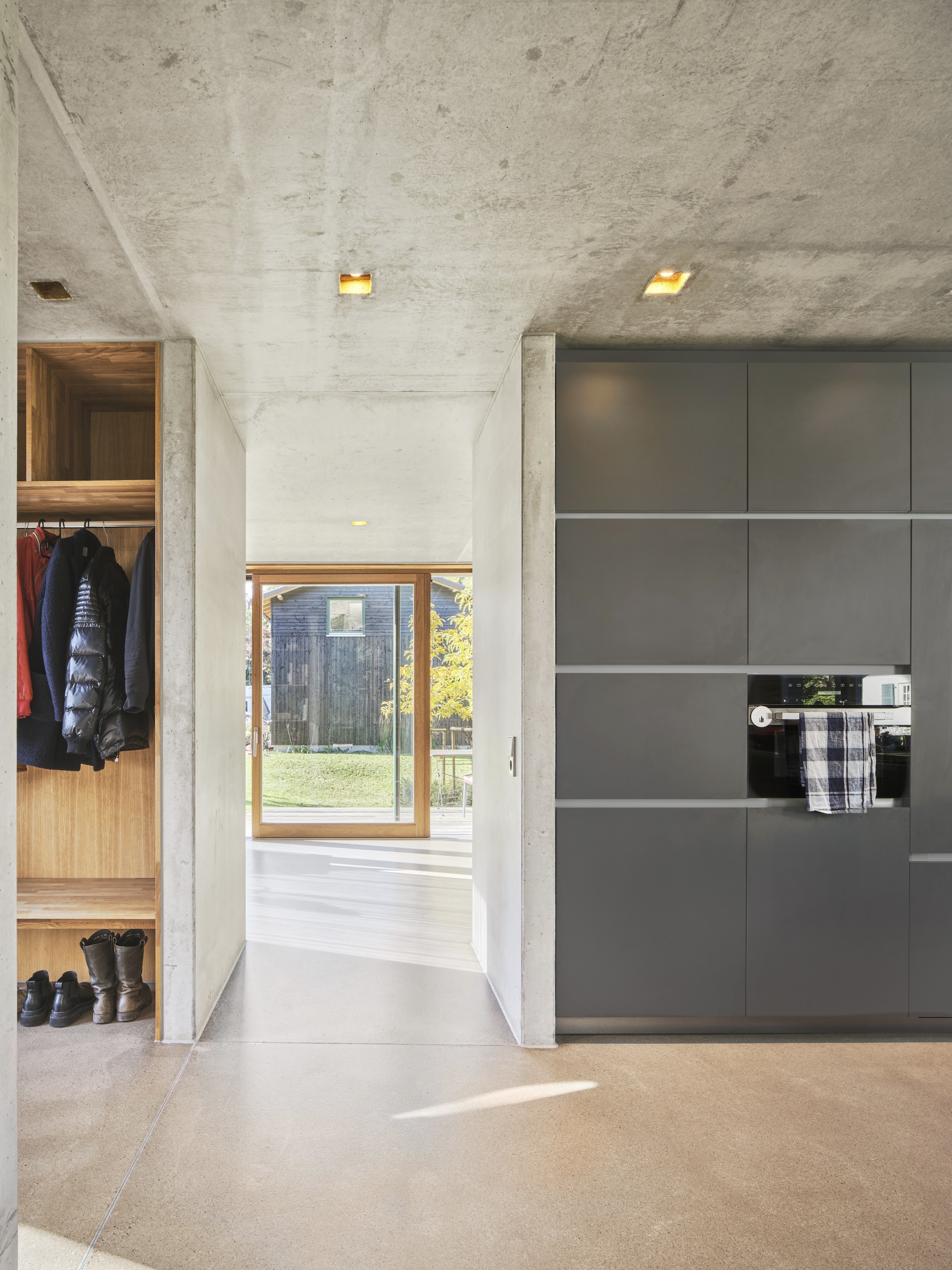 Kitchen passage with gray cabinetry and concrete ceiling lit by recessed skylights