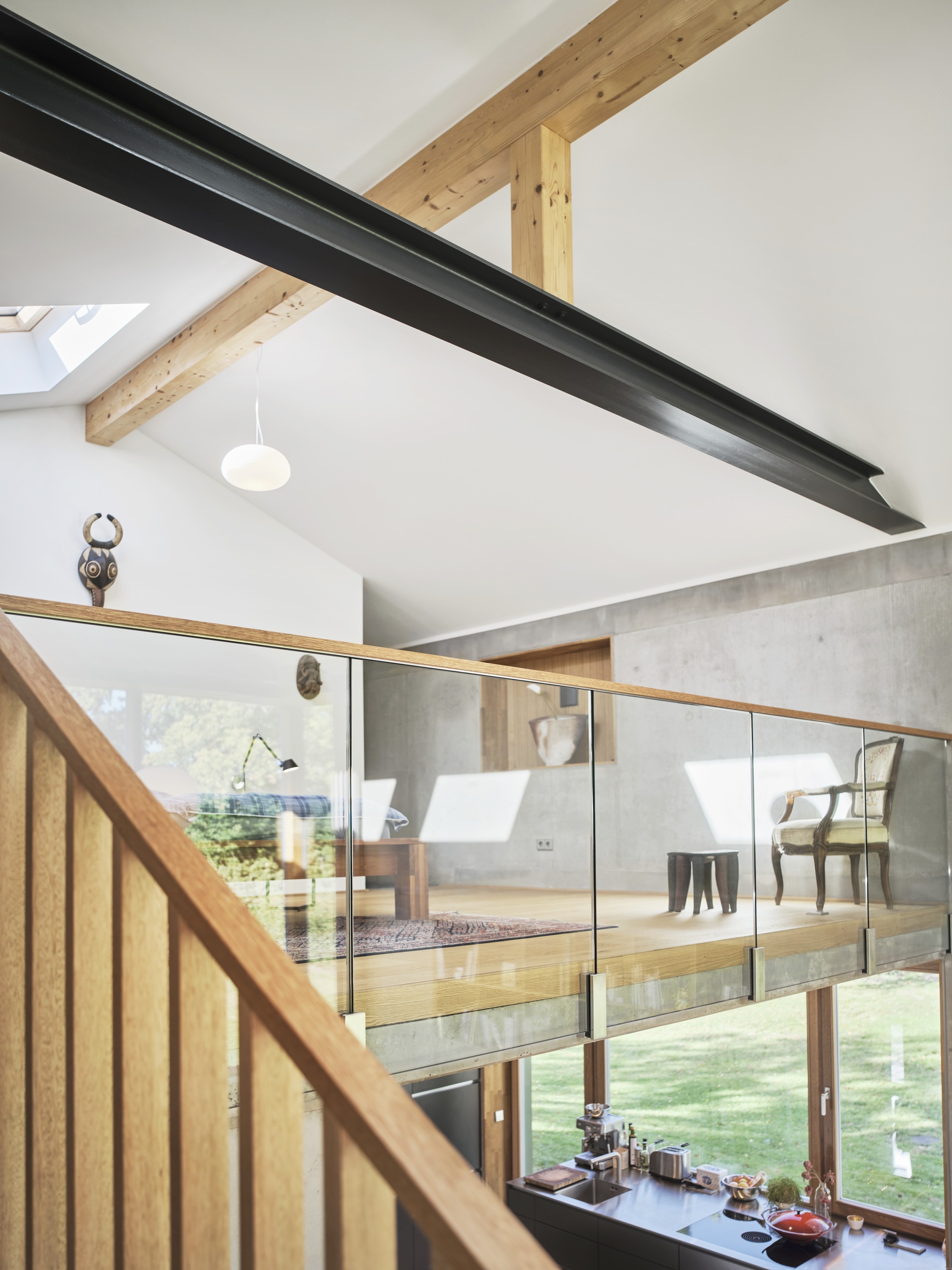 Upper level mezzanine with glass balustrade overlooking double-height space and exposed timber rafters