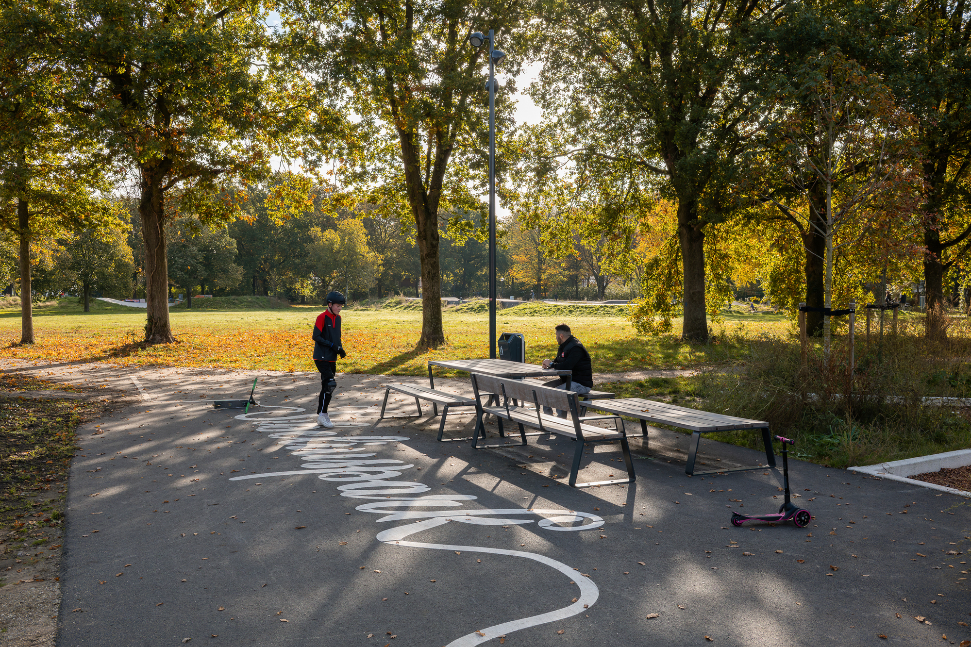 Ping pong table on a curved paved court with tree shadows in autumn