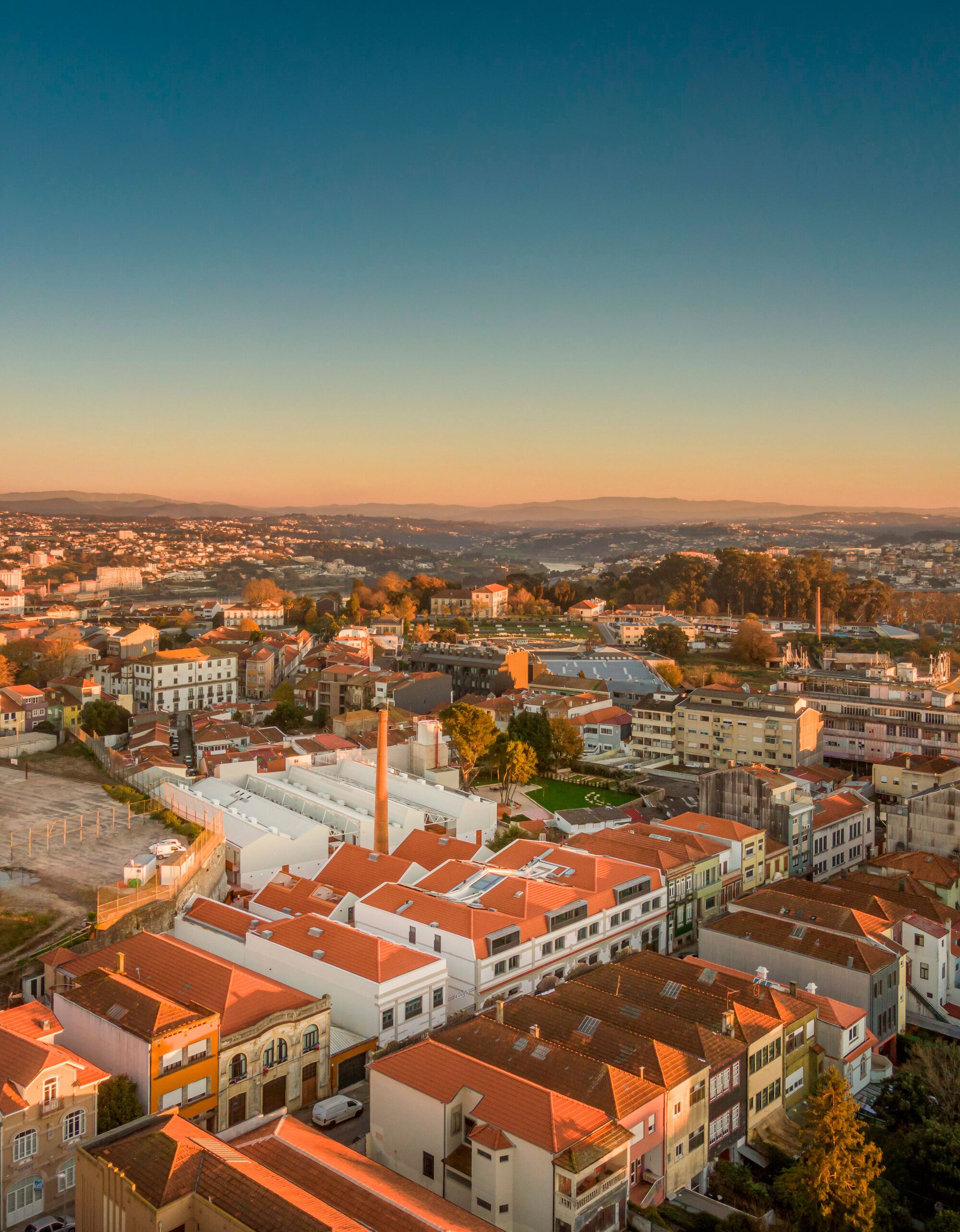 Drone view of mixed-use buildings with terracotta roofs and white facades at sunset
