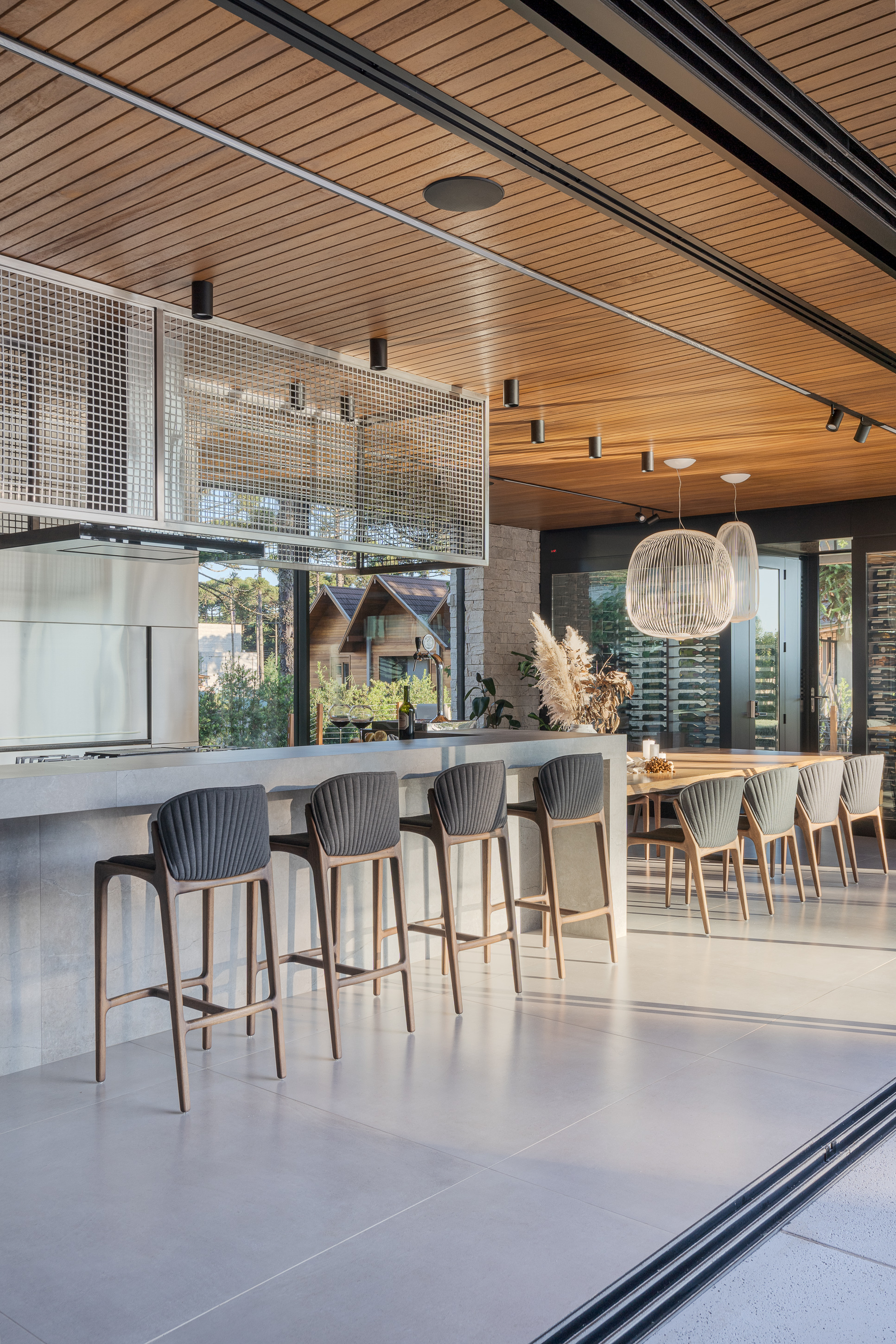 Kitchen island with bar seating beneath a slatted wood ceiling and black track rails