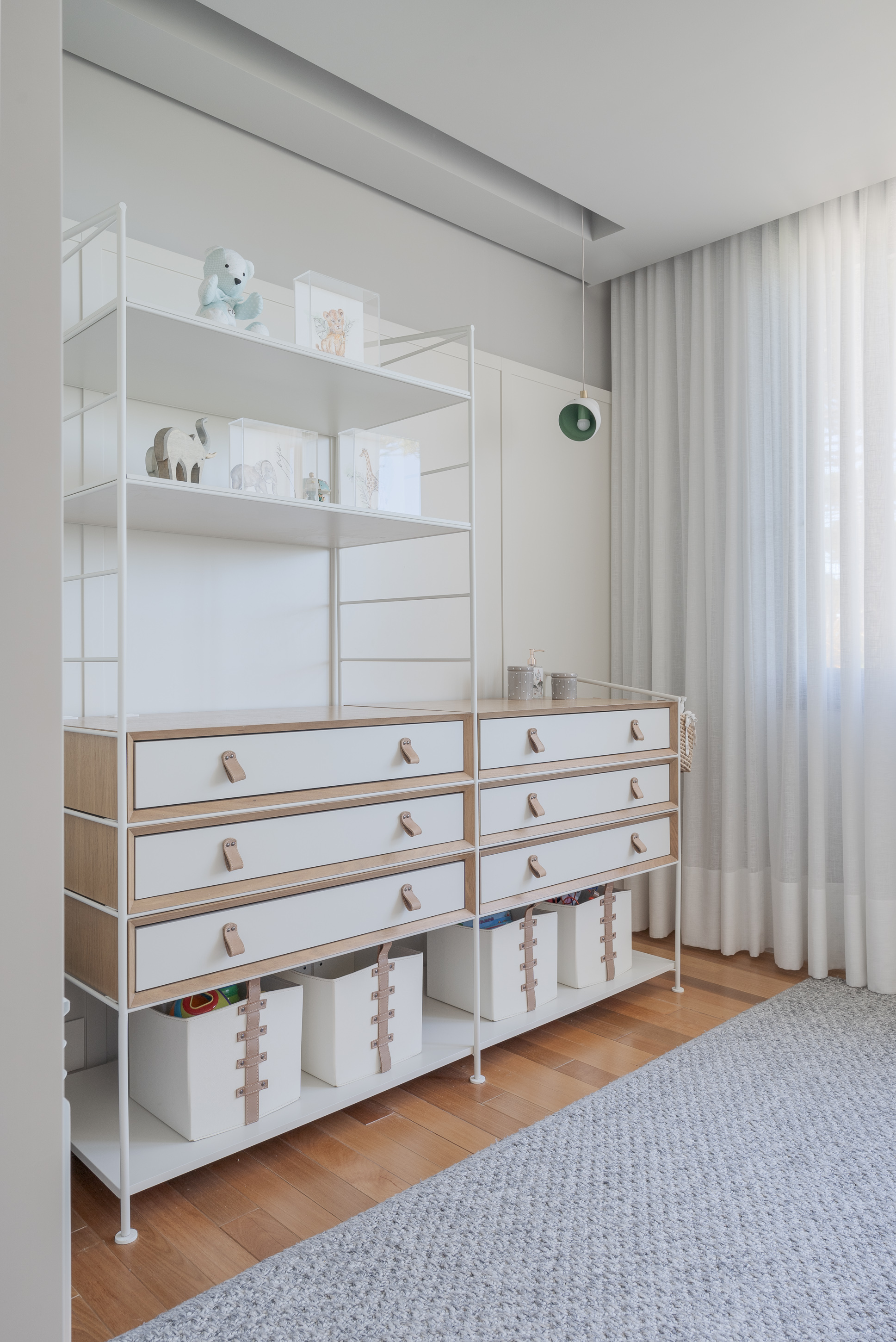 Freestanding white shelving unit with timber-edged drawers and open storage bins on wood flooring