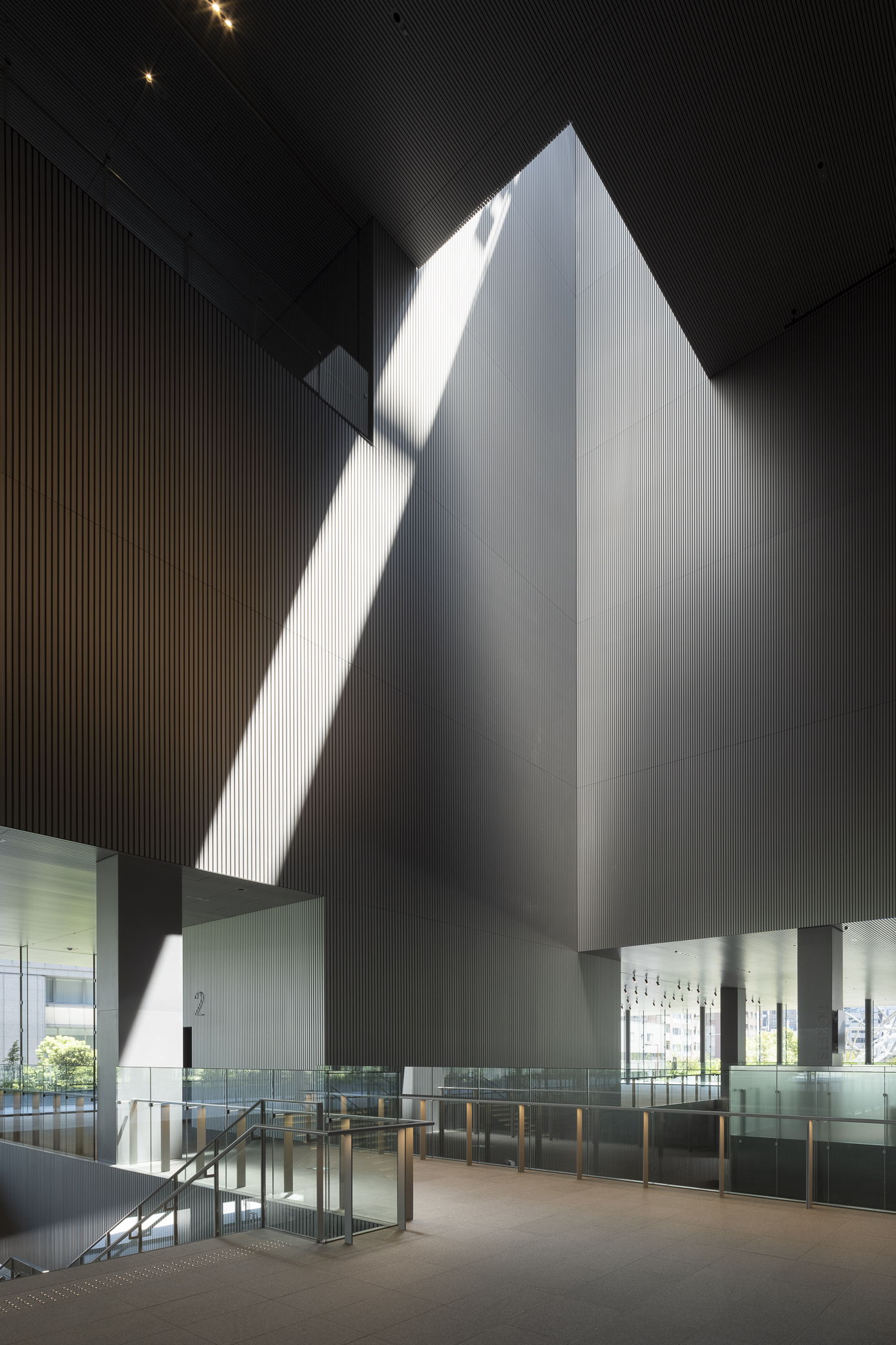 Tall pyramidal volume illuminated by dramatic daylight slicing through the dark ribbed ceiling