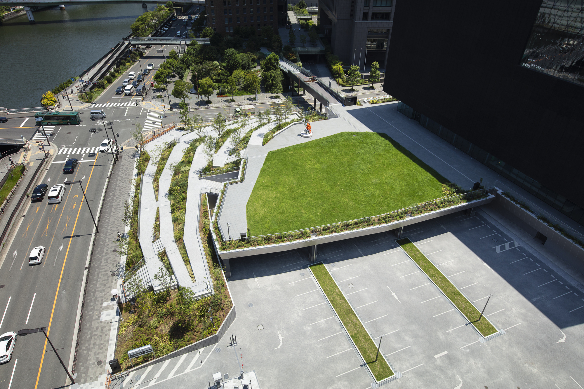 Aerial view of the rooftop lawn and curving planted beds adjacent to parking and roadway