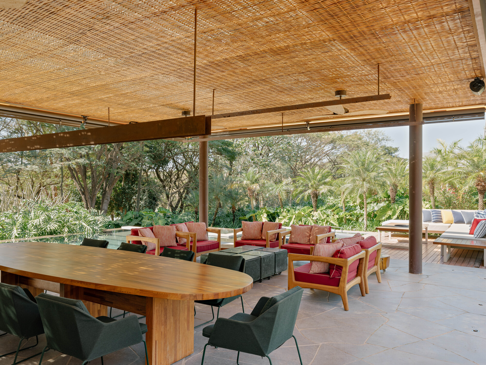 Covered terrace with woven bamboo ceiling and steel columns overlooking planted garden