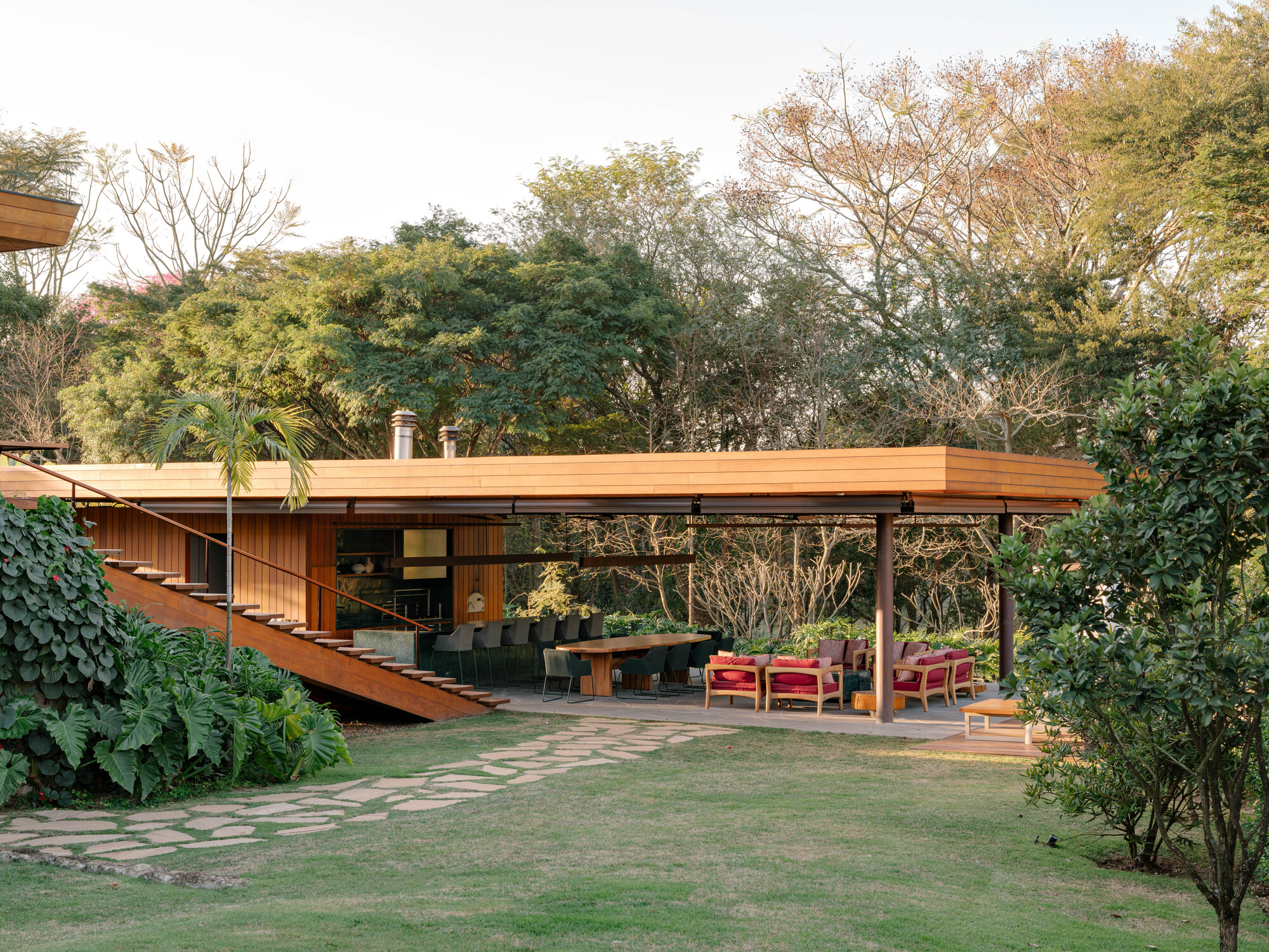 Rear courtyard showing the timber roof pavilion and exterior stair amid lawn and foliage
