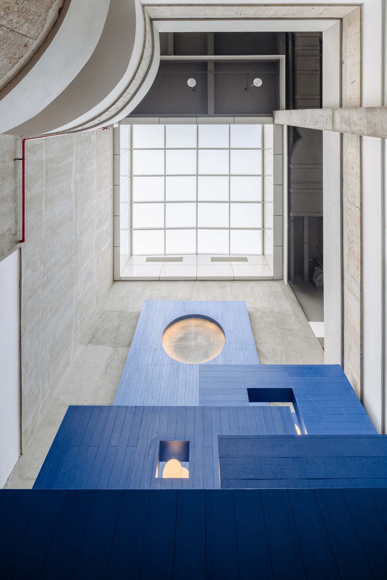 Overhead view of interlocking floor levels with circular openings and a translucent gridded skylight