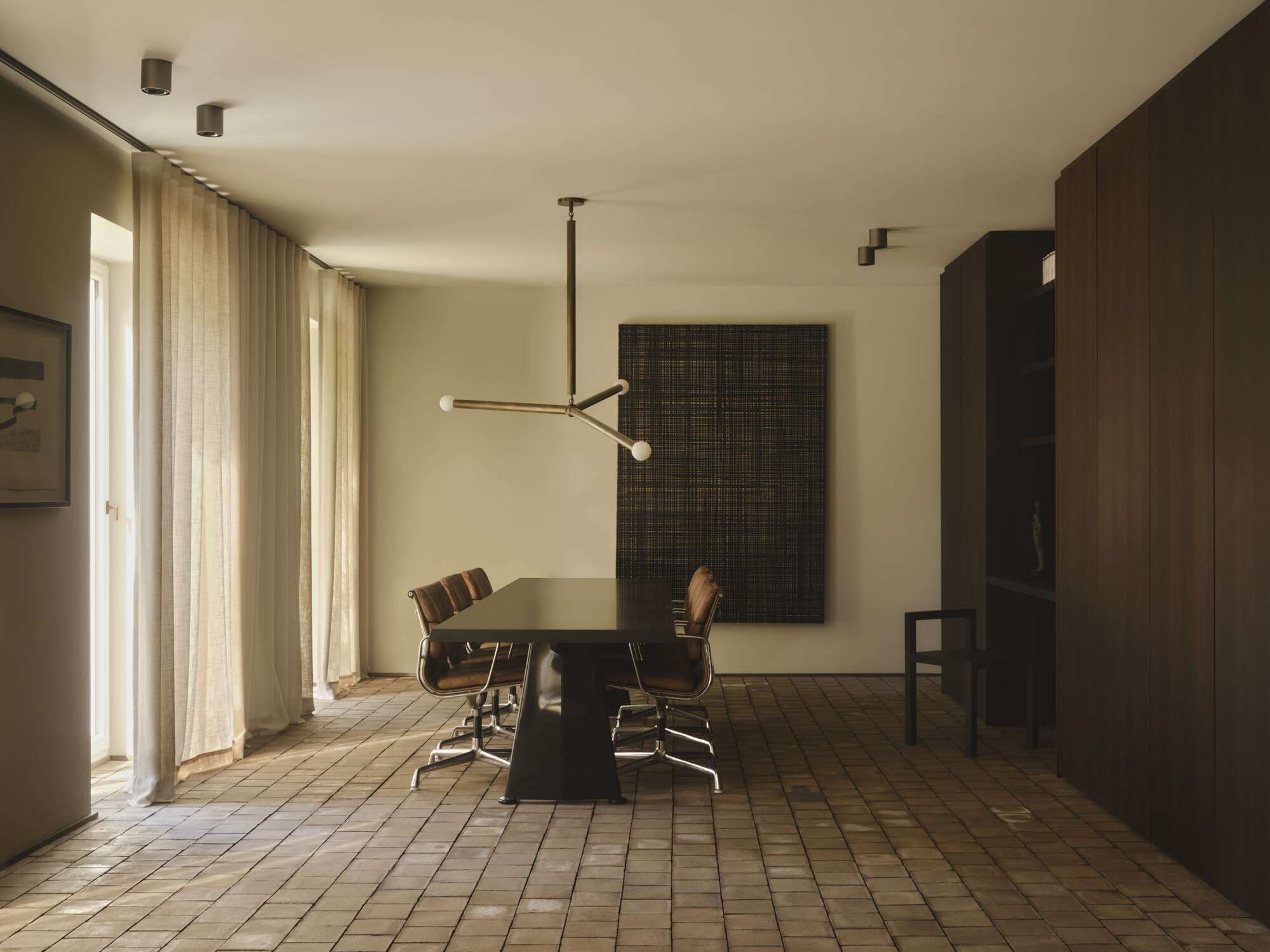 Dining room with small square tile floor and suspended brass chandelier in warm afternoon light