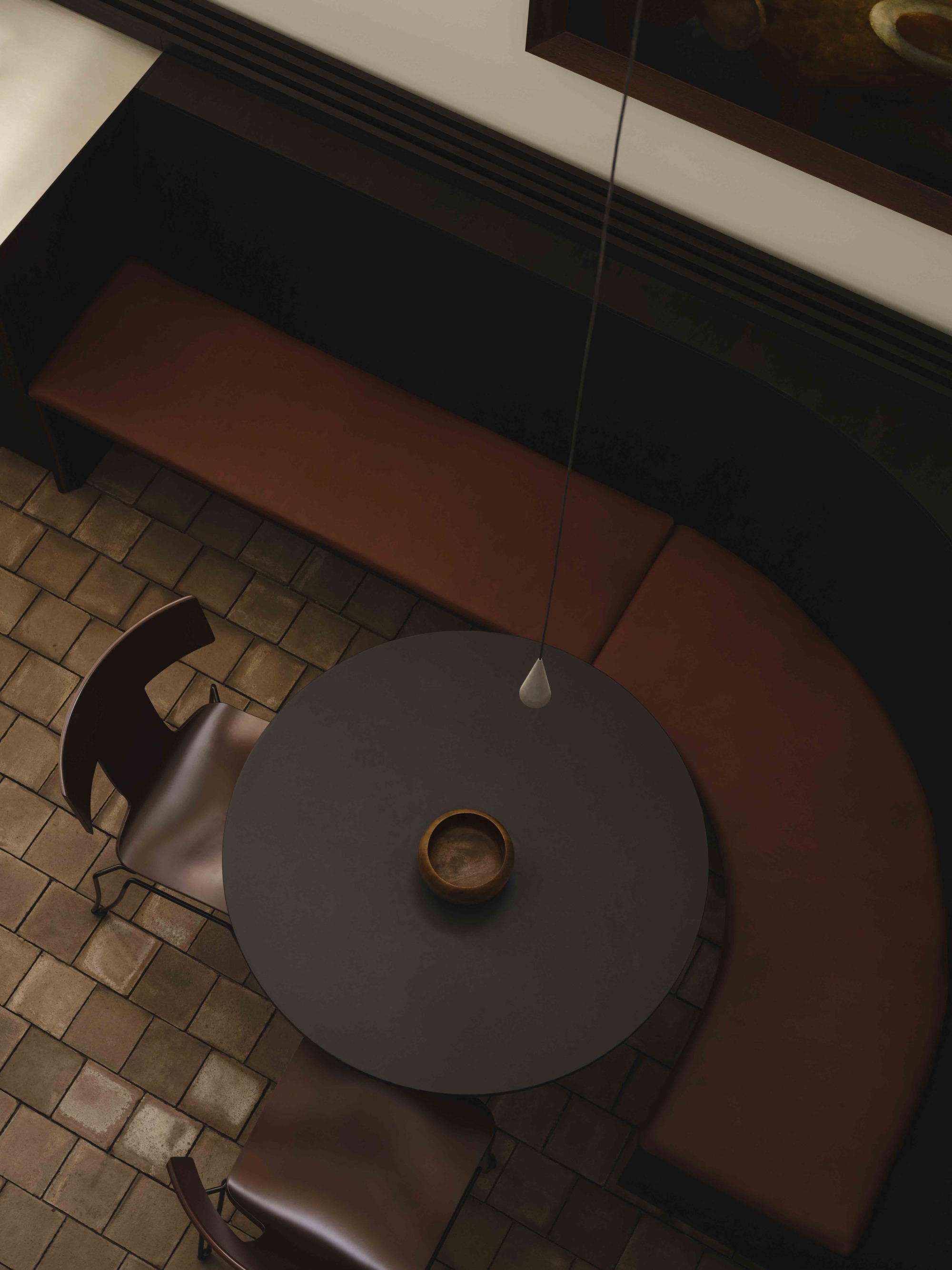 Top-down view of a round dining table with chairs over terracotta tile and cream floor zones