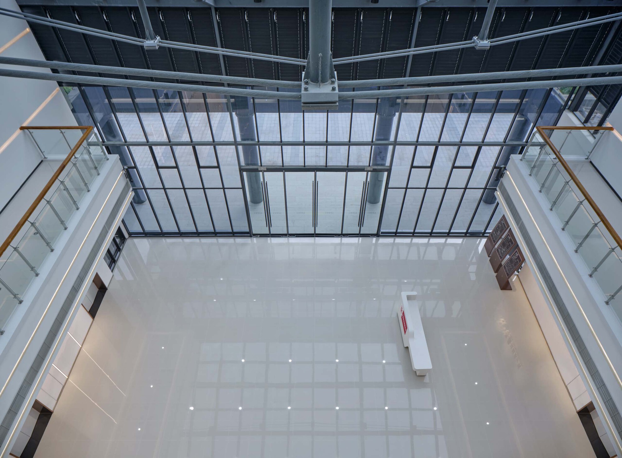 Overhead view of the central atrium with a glazed roof and white tiled floor below