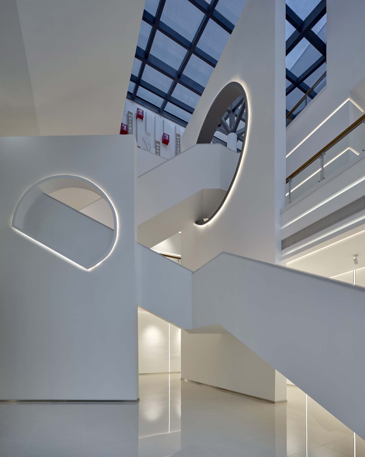 Curved white staircase with integrated LED lighting rising through the multi-level atrium