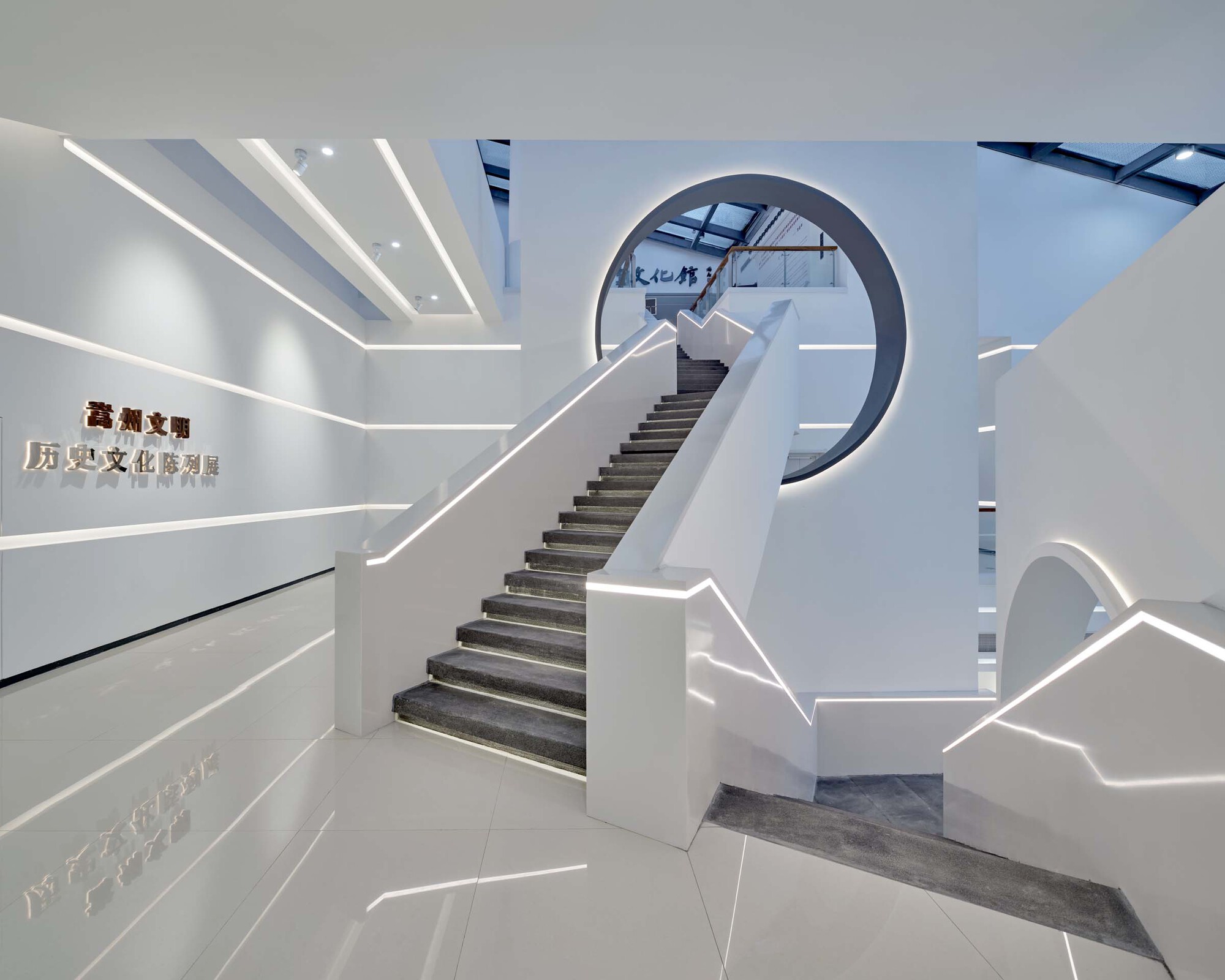 Entry lobby featuring a sculptural staircase with edge-lit handrails and skylights above