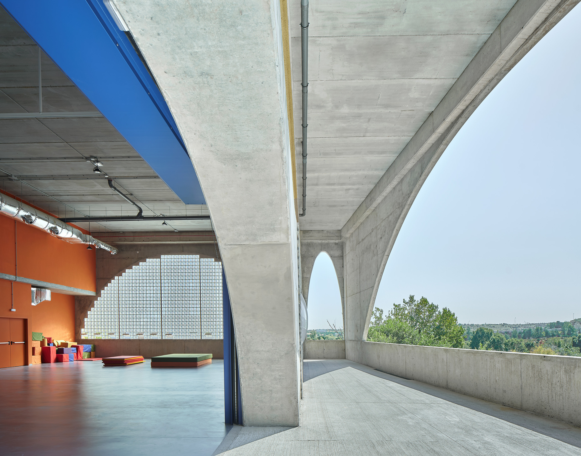 Covered terrace with board-formed concrete arch opening to a distant tree line