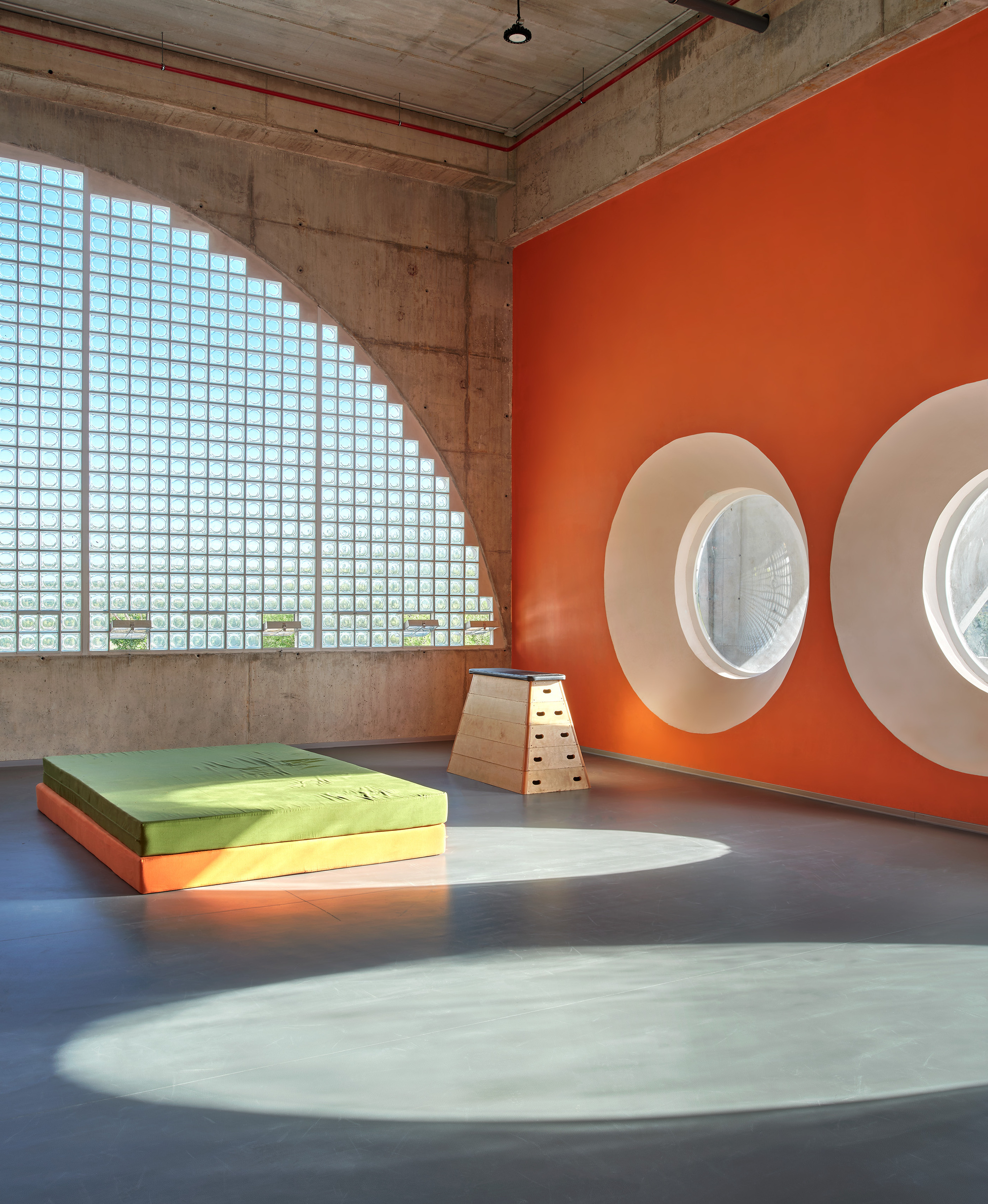 Interior room with glass block wall casting shadow on orange wall with circular porthole windows