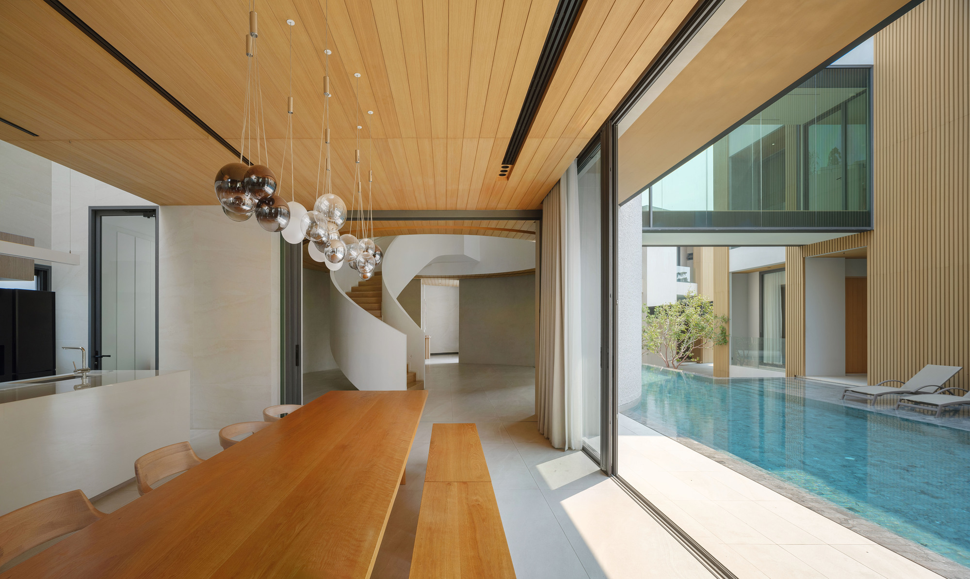 Dining room with timber ceiling and glass pendant lights overlooking a courtyard pool